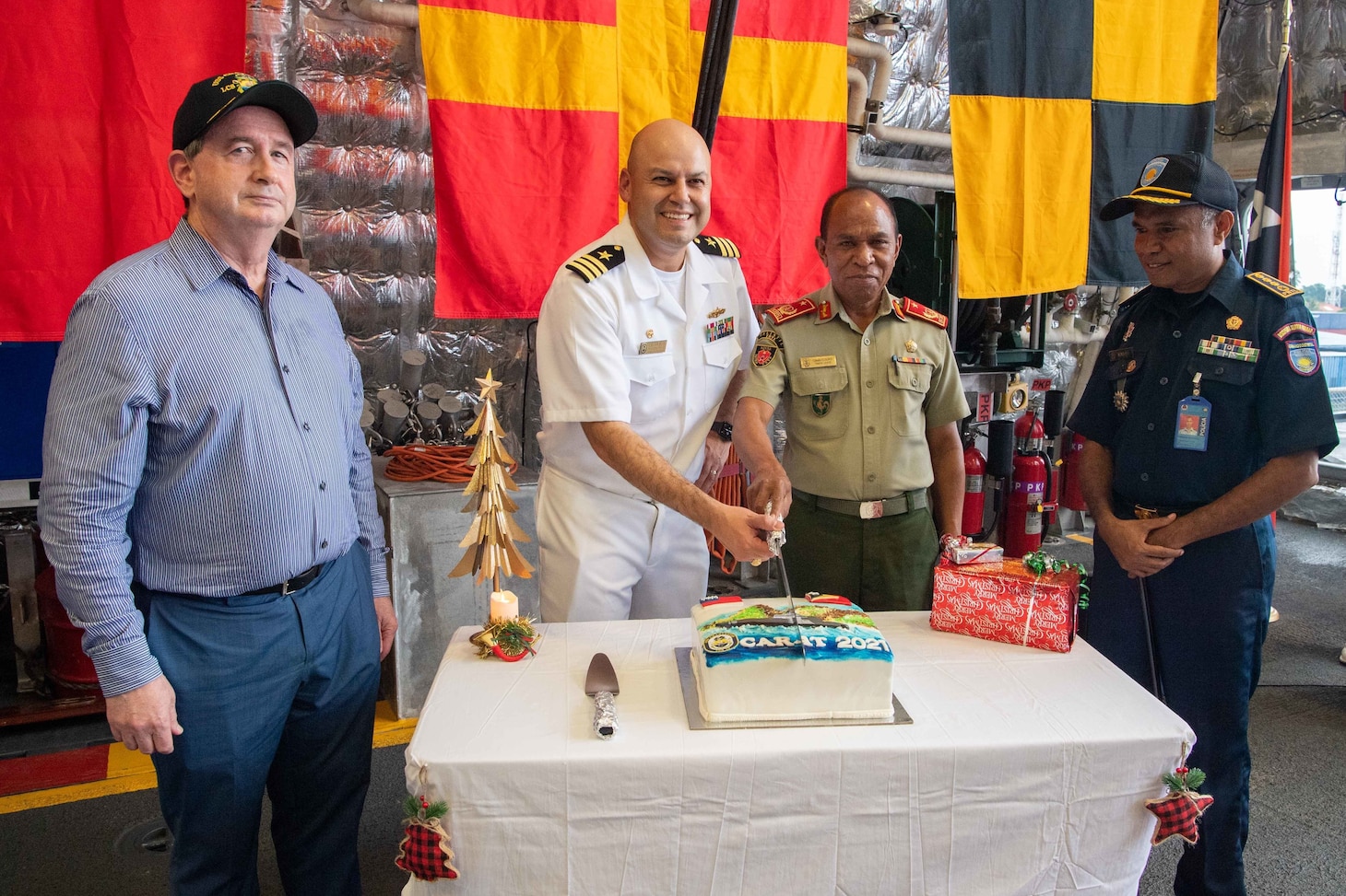 DILI, Timor-Leste (Dec. 8, 2021) Left to right, Thomas E. Daley, charge d’affaires, United States Embassy, Cmdr. Clayton Beas, commanding officer of Independence-variant littoral combat ship USS Charleston (LCS 18), Brig. Gen. Calisto “Coliati” dos Santos, Chief of Staff Timor-Leste Defense Force, and Chief Superintendent Henrique da Costa, Timor-Leste National Police, participate in a cake cutting ceremony in the hangar bay during a reception in Dili, Timor-Leste. Charleston, part of Destroyer Squadron (DESRON) 7, is on a rotational deployment in the U.S. 7th Fleet area of operation to enhance interoperability with partners and serve as a ready-response force in support of a free and open Indo-Pacific region. (U.S. Navy photo by Mass Communication Specialist 2nd Class Ryan M. Breeden)