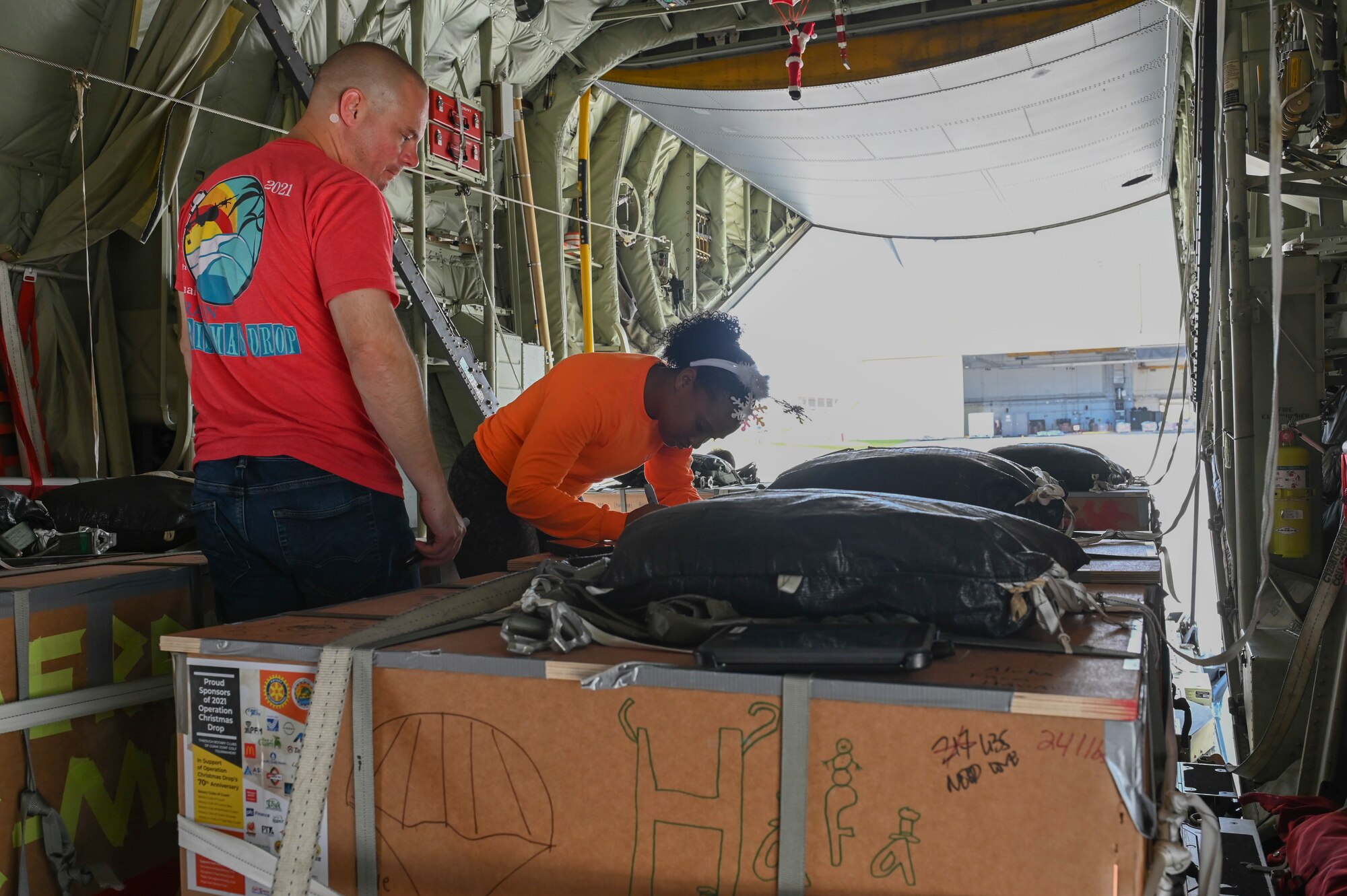 One person signing a package on a plane while the her one watches over her.