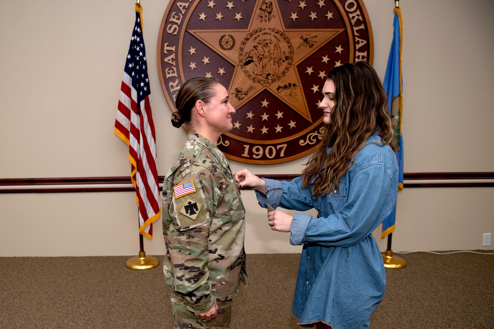 Oklahoma National Guard Master Sgt. Megan Mathews, battalion operations sergeant with the 1st Battalion, 160th Field Artillery Regiment, 45th Infantry Brigade Combat Team, stands as her daughter, Nora, pins on her new rank at her promotion ceremony held at Joint Force Headquarters in Oklahoma City, Dec. 15, 2021. (Oklahoma National Guard photo by Sgt. 1st Class Mireille Merilice-Roberts)