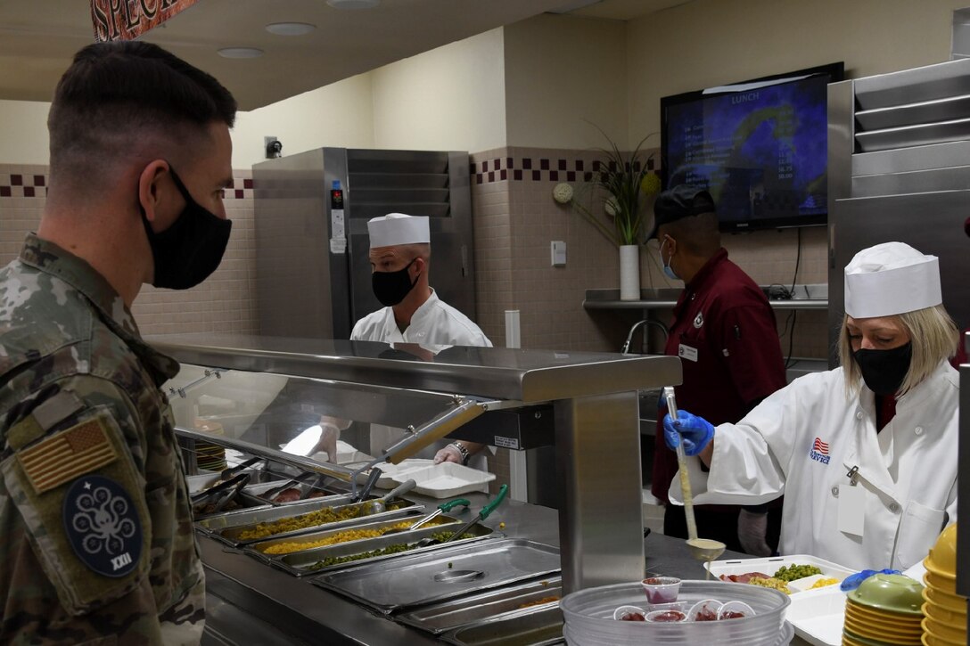 Heather Warakomski serves lunch to an Airman at the Satellite Dish dining facility on Schriever Space Force Base, Colorado, Dec. 15, 2021. Warakomski joined U.S. Space Force Col. Shay Warakomski, Peterson-Schriever Garrison commander and Schriever SFB leaders to celebrate the upcoming holiday season by serving Airmen, Guardians, and civilians during their lunch break.