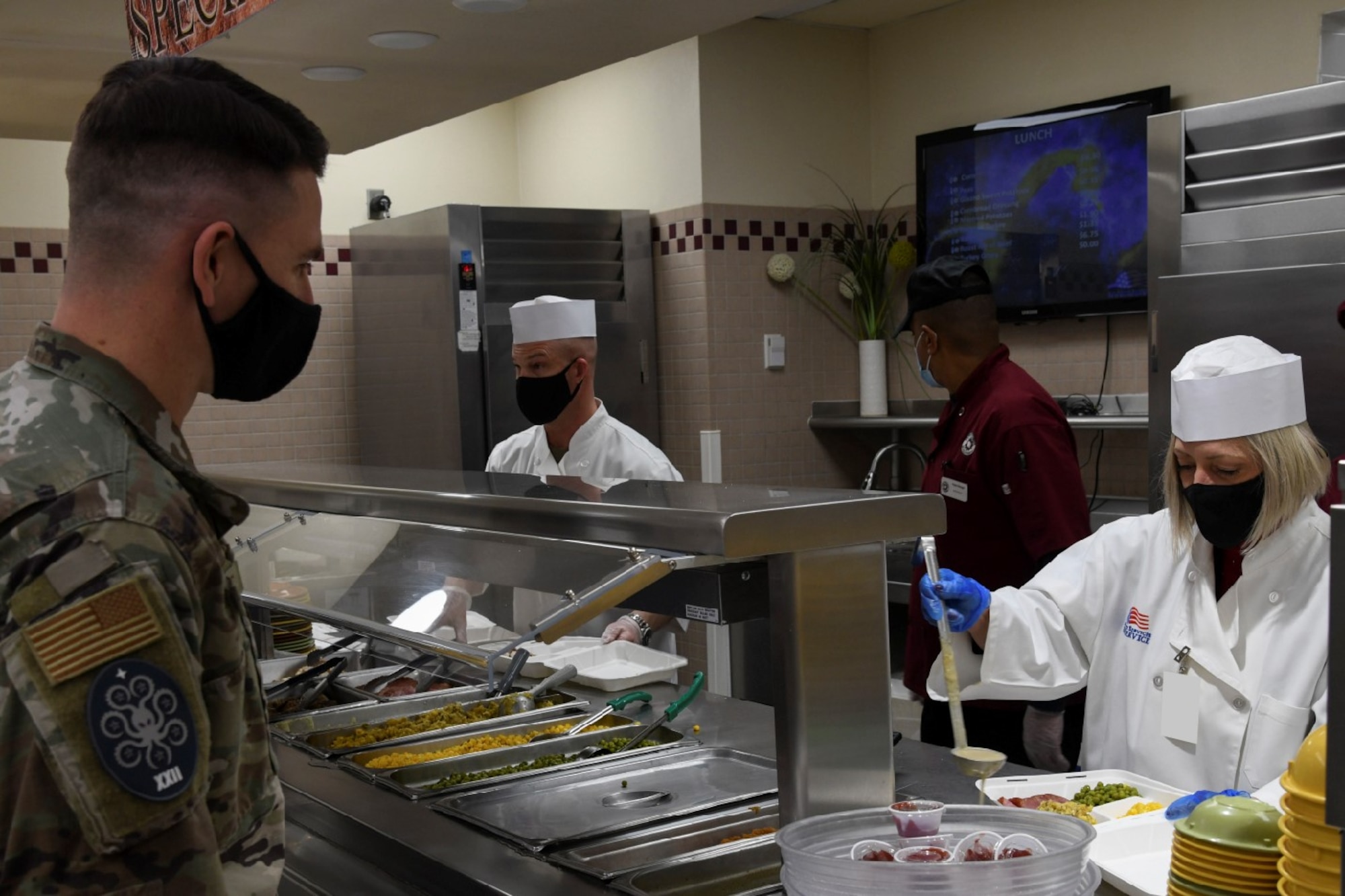 Heather Warakomski serves lunch to an Airman at the Satellite Dish dining facility on Schriever Space Force Base, Colorado, Dec. 15, 2021. Warakomski joined U.S. Space Force Col. Shay Warakomski, Peterson-Schriever Garrison commander and Schriever SFB leaders to celebrate the upcoming holiday season by serving Airmen, Guardians, and civilians during their lunch break.