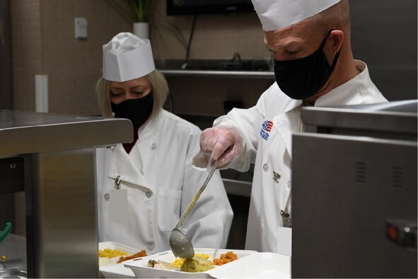 U.S. Space Force Col. Shay Warakomski, Peterson-Schriever Garrison commander, and his spouse, Heather, serve holiday meals to Guardians, Airmen and civilians at the Satellite Dish dining facility on Schriever Space Force Base, Colorado, Dec. 15, 2021.