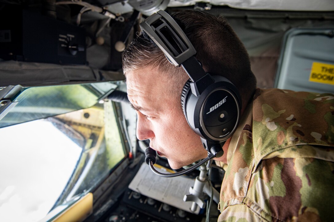 A boom operator looks out the back window as he fuels an aircraft