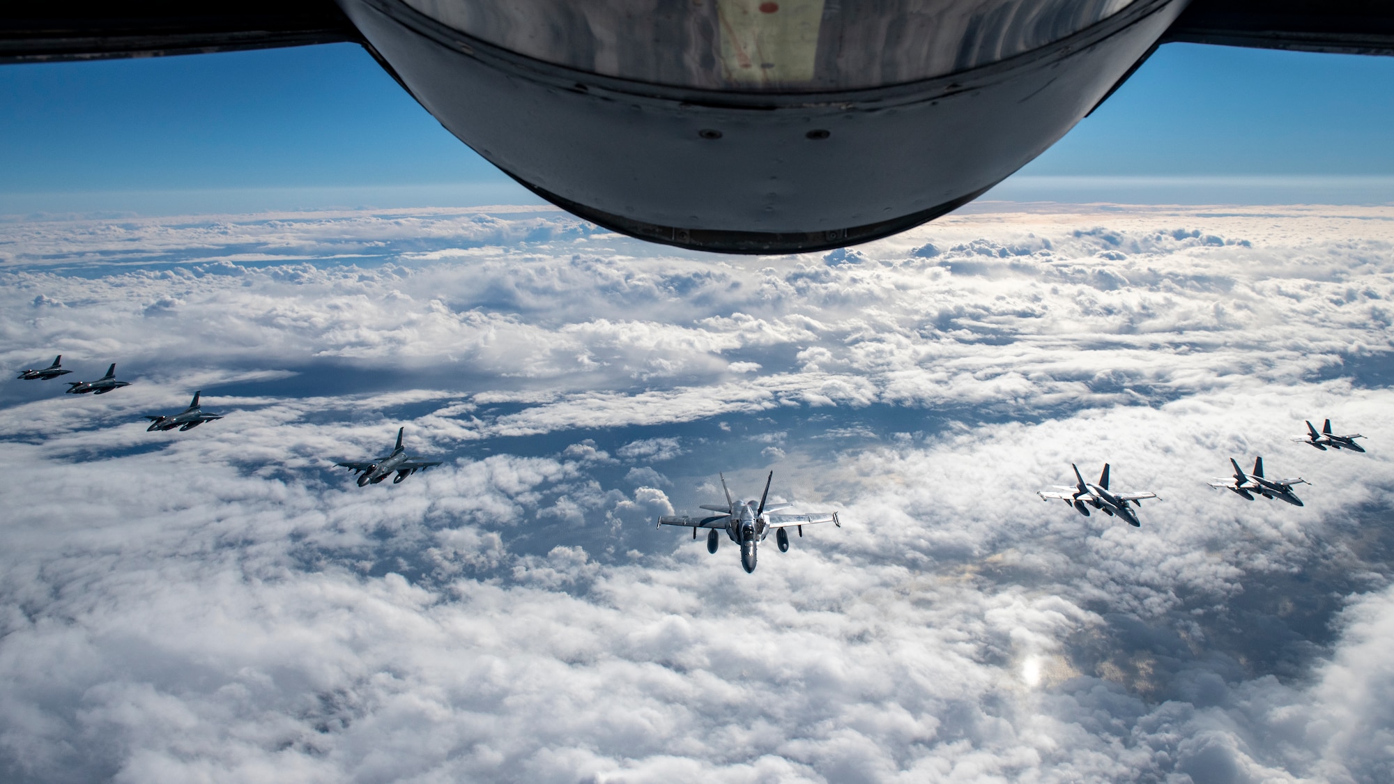 8 F-2 and F/A-18C aircraft fly in formation behind a KC-135R Stratotanker.