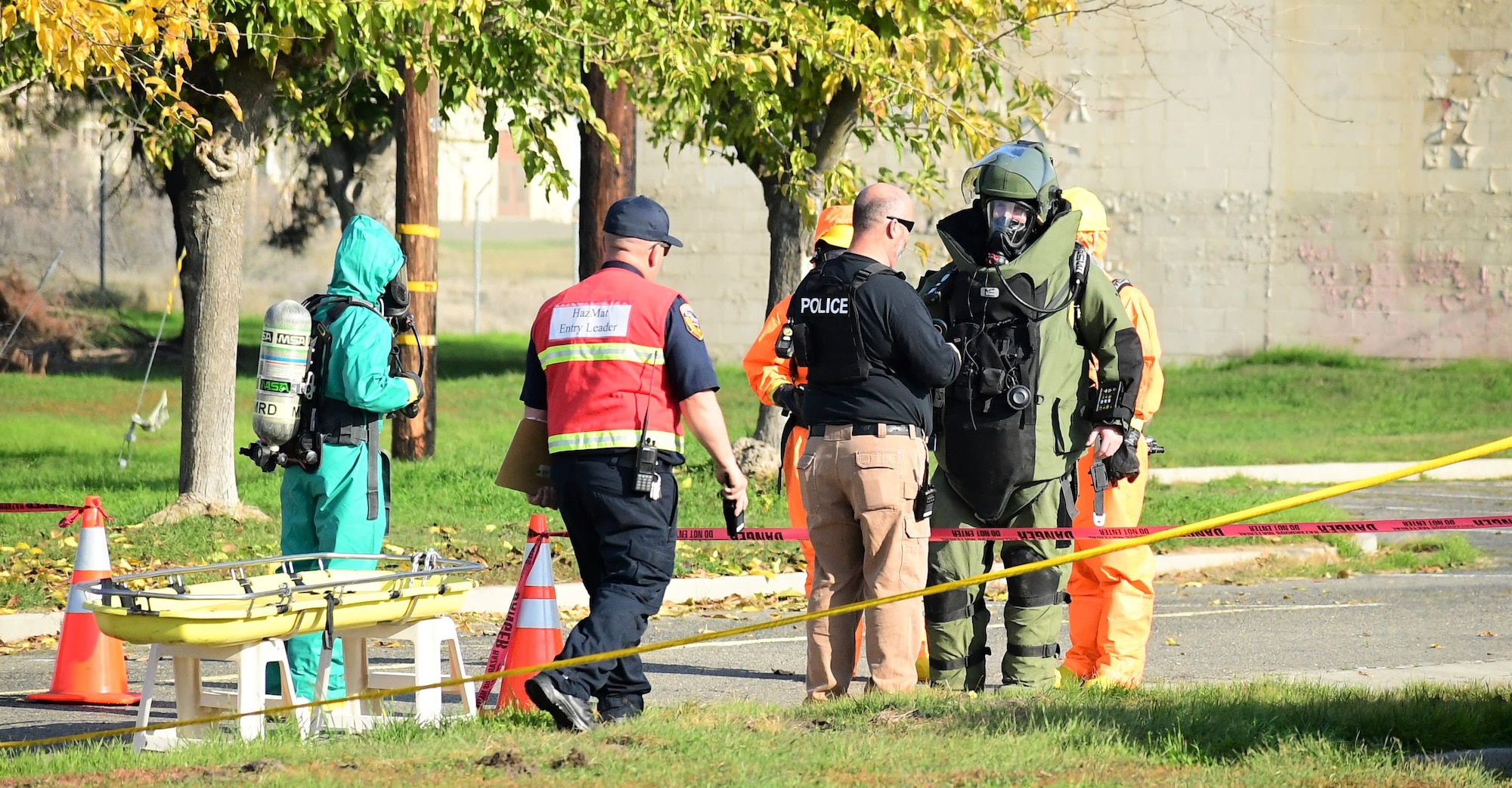 A Merced County police explosive ordnance disposal specialist in his green, heavily armored blast suit reports his findings to local law enforcement and the CAL FIRE hazmat specialist during a joint exercise with California National Guard’s 9th and 95th Civil Support Team at Castle Air Force Base in Atwater, California, Dec. 1, 2021. The event promotes interoperability and communication between local, state and federal agencies.
