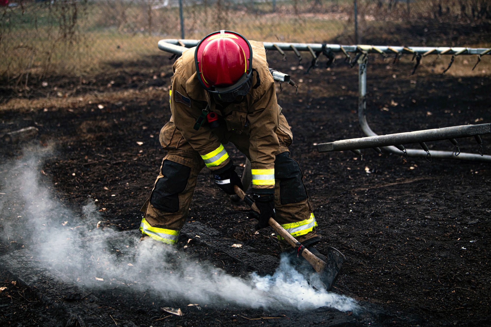 An firefighter uses an axe to prevent embers from re-sparking
