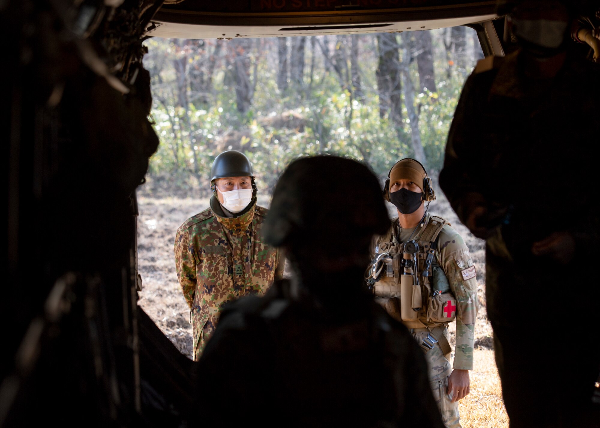A Japanese Captain and a U.S. aviator watch soldiers perform medical evac drills.