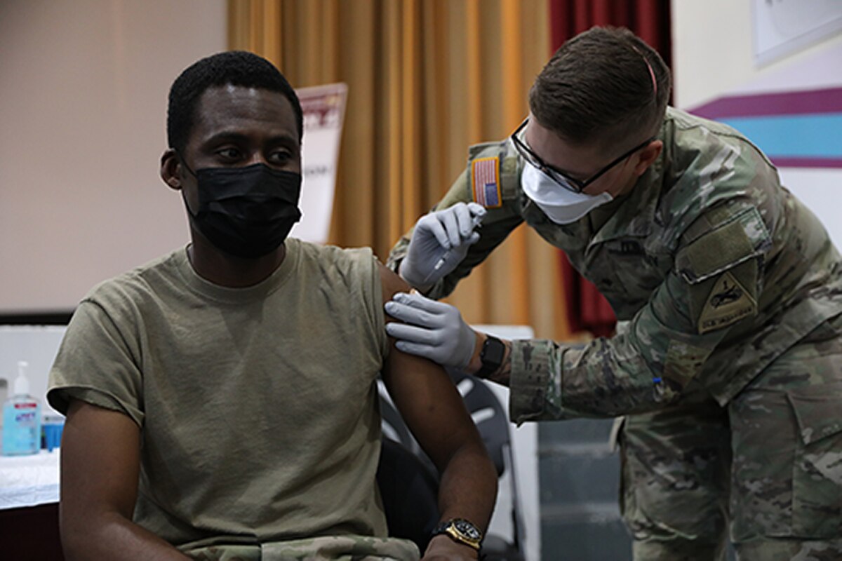 A soldier is vaccinated by another soldier.