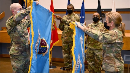 Army Lt. Gen. (Dr.) Ronald Place, director of the Defense Health Agency (left), and Air Force Maj. Gen Shanna Woyak, Small Market and Stand Alone Military Treatment Facility Organization director (right), unfurl the organization flags during the SSO establishment ceremony at Joint Base San Antonio-Kelly Field, Texas, Dec. 14 (Photo by Brian Boisvert).