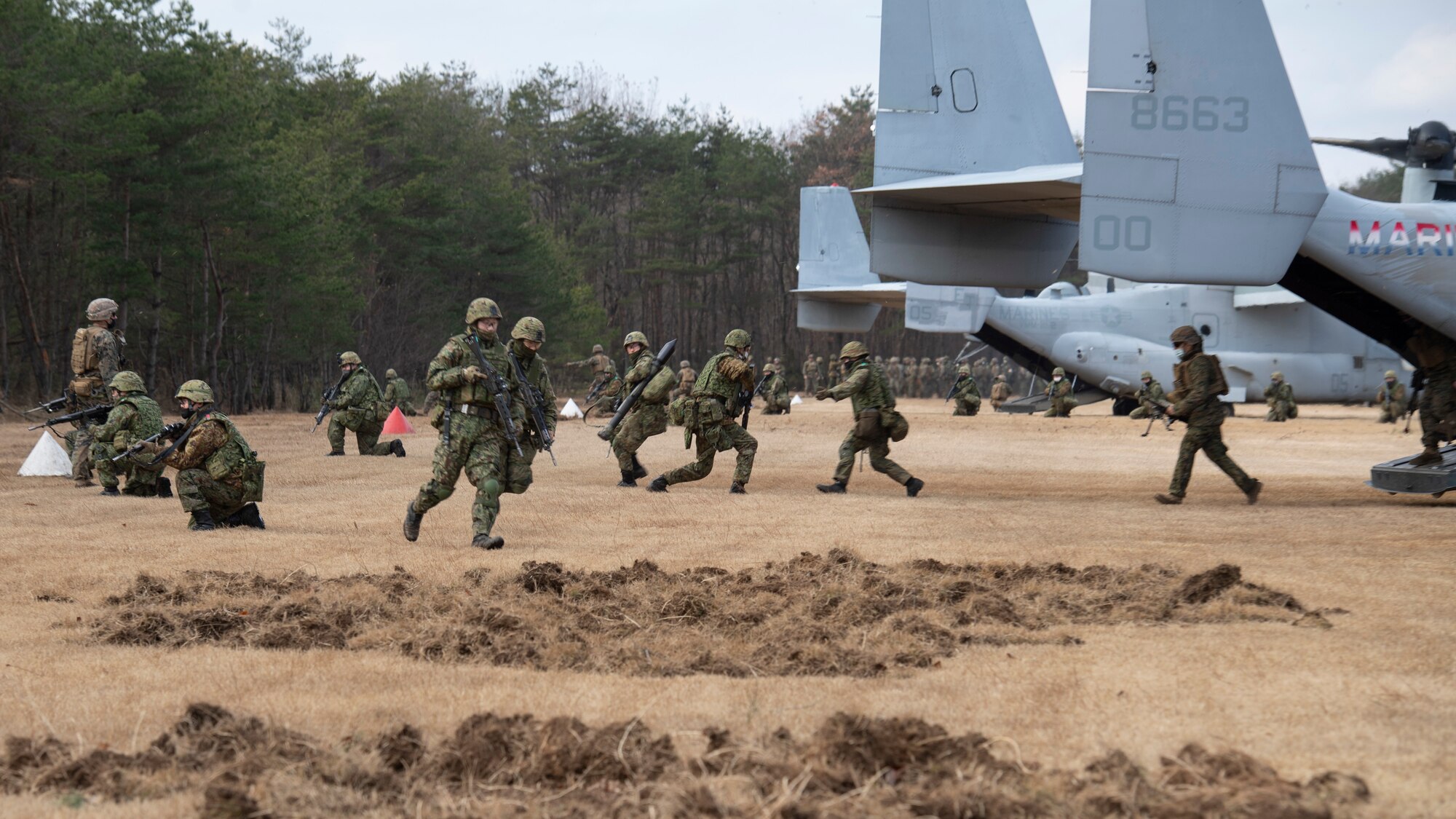 U.S. and Japanese soldiers form a parameter around a landed helicopter.