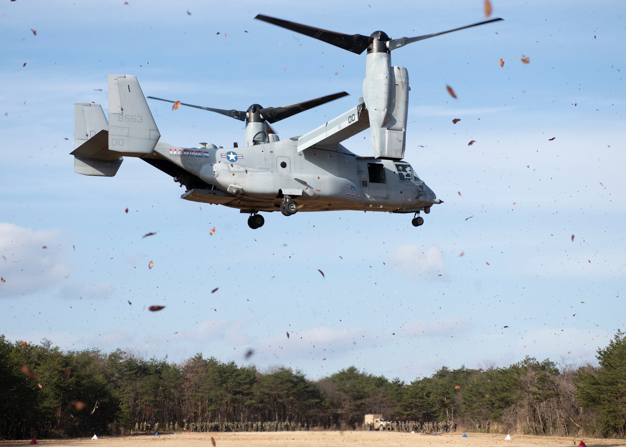 A Marine helicopter comes in for a landing on a grassy field.