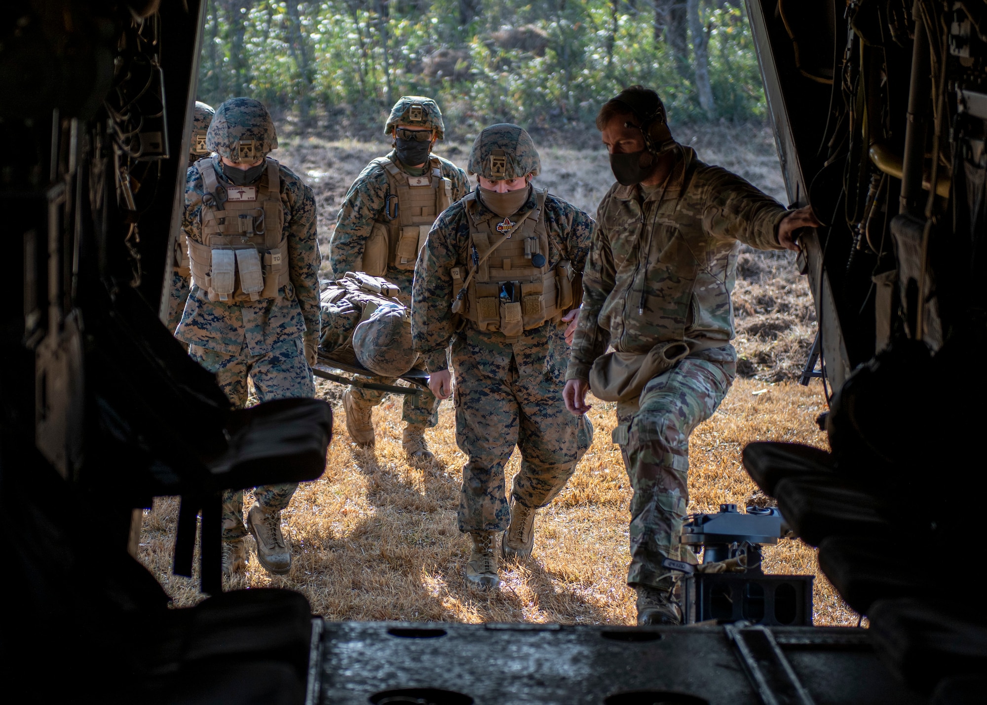 Four marines carry a fifth on a stretcher into a helicopter.