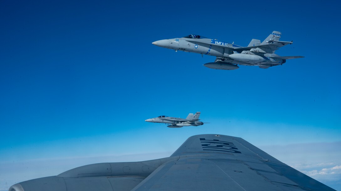 Two F/A-18C Hornets fly next to a KC-135R after refueling.