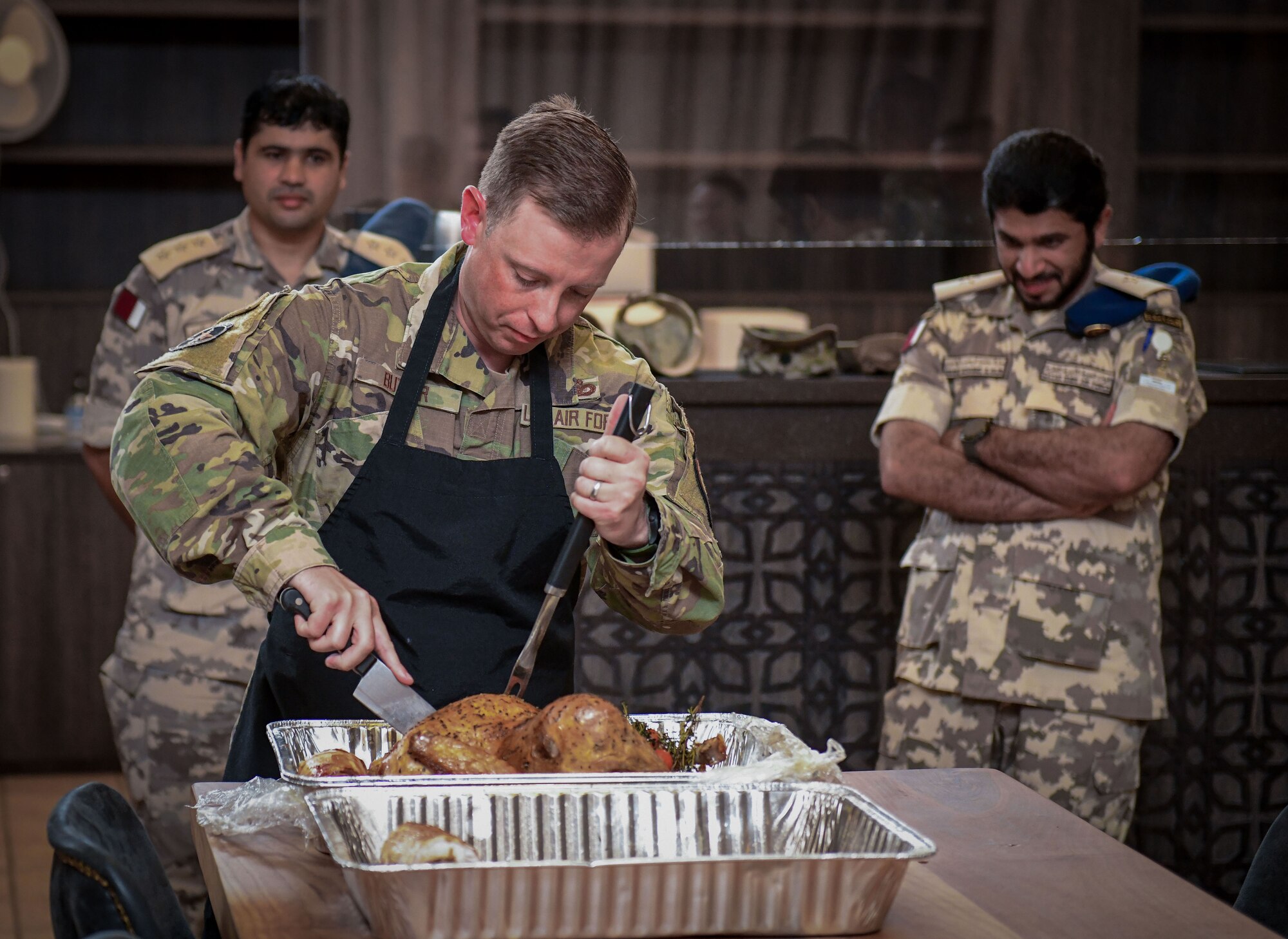 U.S. service member carves turkey during meal.