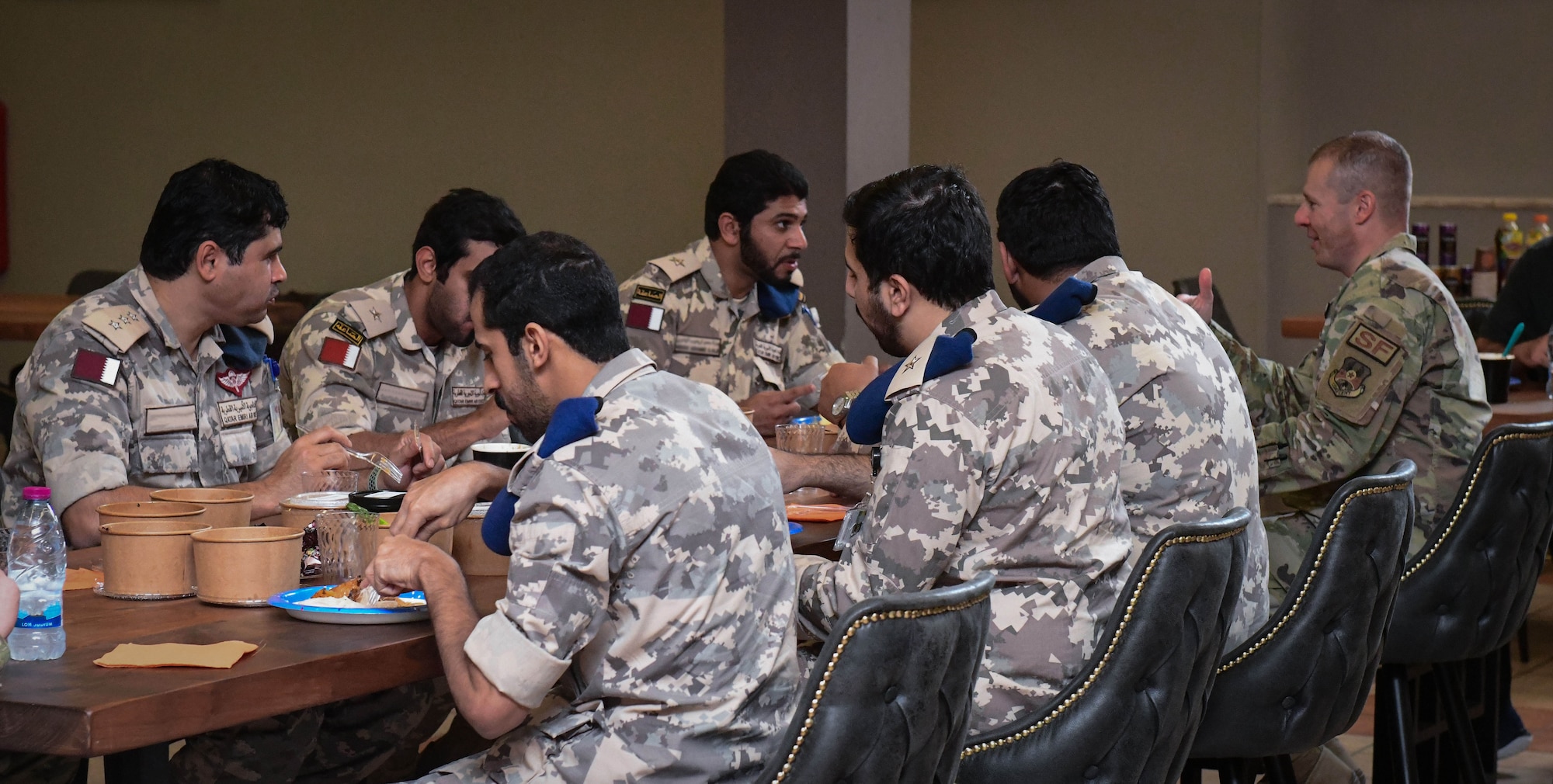 U.S. and Qatari service members sit down for a meal.