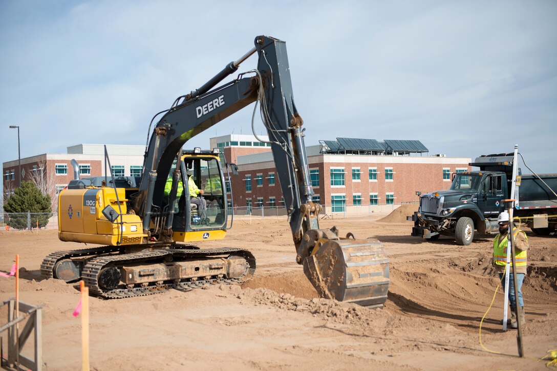 Construction workers move dirt while working on the new fitness center