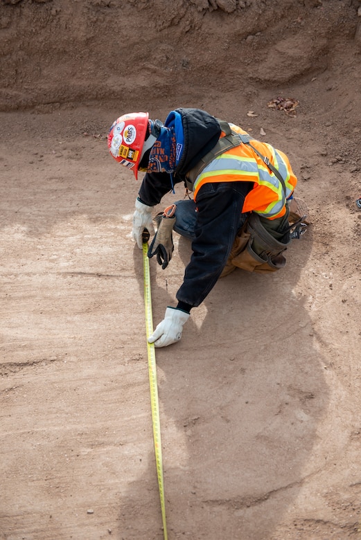 A construction worker double checks the measurement of  the footprint of the indentation they've created while working on the new fitness center