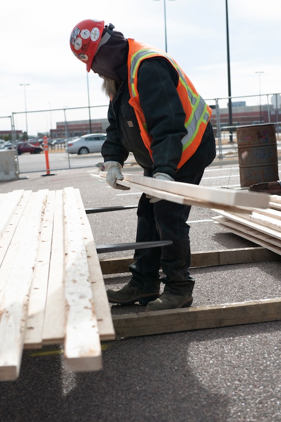 A construction worker loads lumber that will be used in the new fitness center being constructed