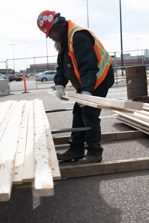 A construction worker loads lumber that will be used in the new fitness center being constructed