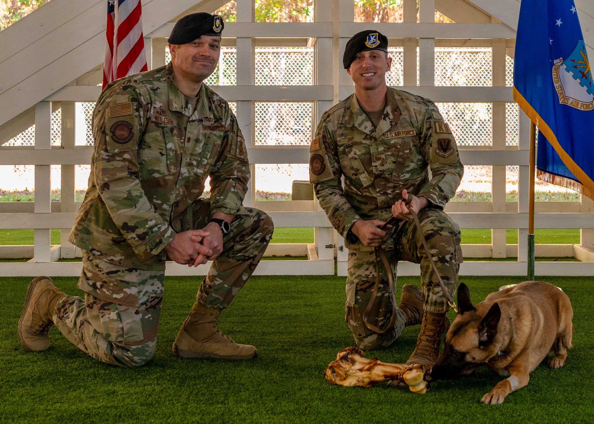 Maj. Michael Wetlesen, 4th Security Forces Squadron commander and Tech. Sgt. Kyle Shy, 4th SFS kennel master present military working dog Tessa her first bone during her retirement ceremony at Seymour Johnson Air Force Base, North Carolina, Nov. 19, 2021.