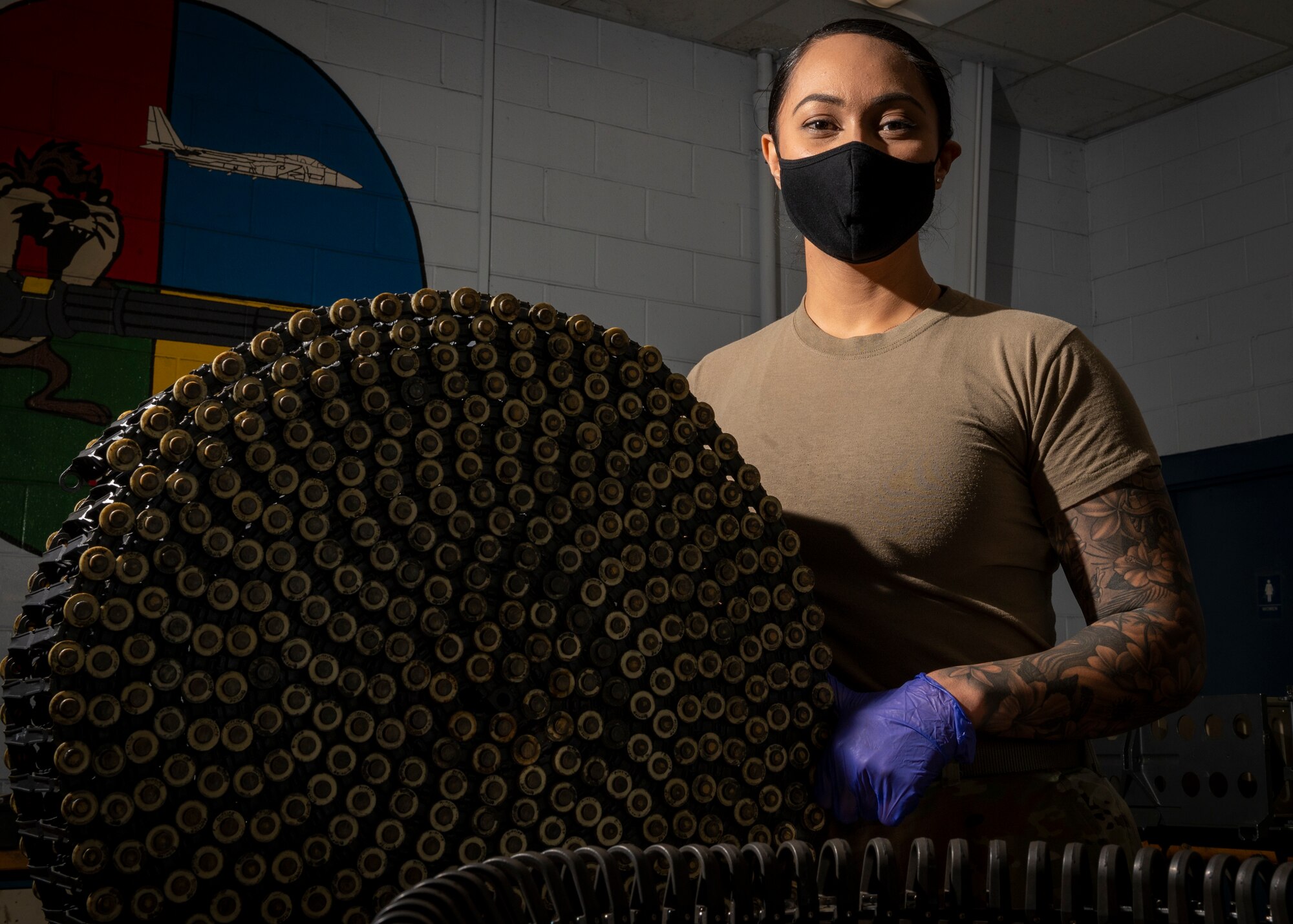Staff Sgt. Dora Pulu, 4th Equipment Maintenance Squadron armament maintenance supervisor, poses next to an ammunition belt, at Seymour Johnson Air Force Base, North Carolina, Nov. 17, 2021.