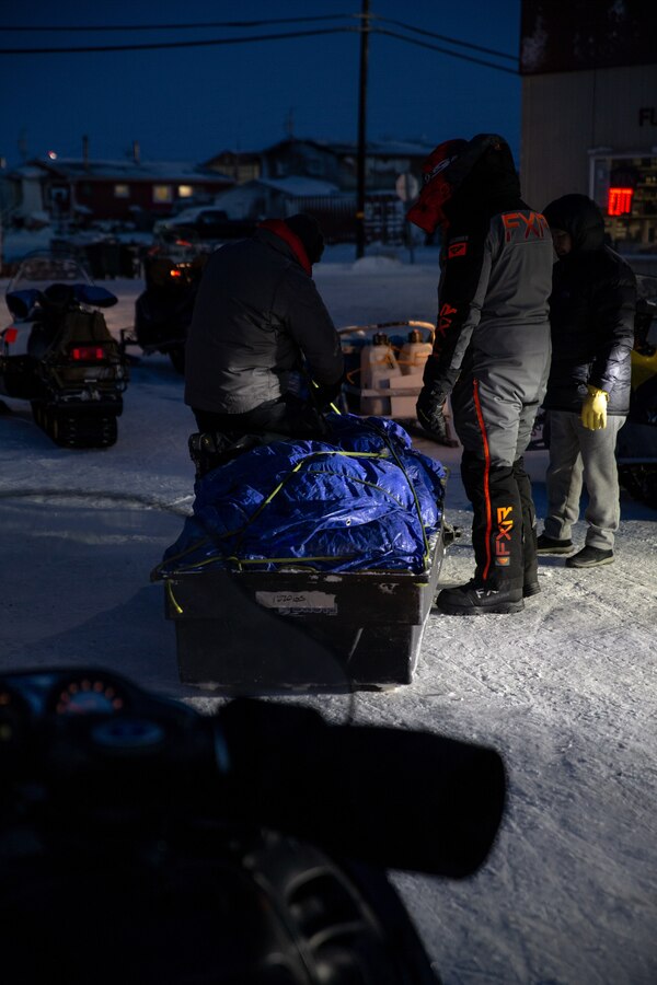 U.S. Marines with Delta Company, 4th Law Enforcement Battalion, Marine Forces Reserve, and local trail guides secure the contents of a sled before departing on snowmobiles in Kotzebue, Alaska, Dec. 12, 2021. The Marine Corps Reserve hosts the Toys for Tots program, collects donations of toys, and delivers them to school-aged children across the United States. (U.S. Marine Corps photo by Cpl. Brendan Mullin)