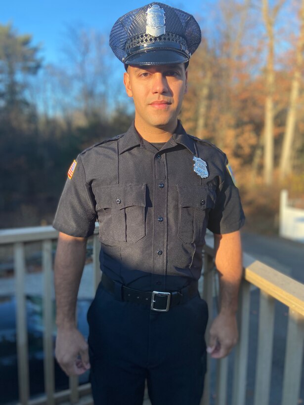 A man in a police uniform and cap poses for a photo.