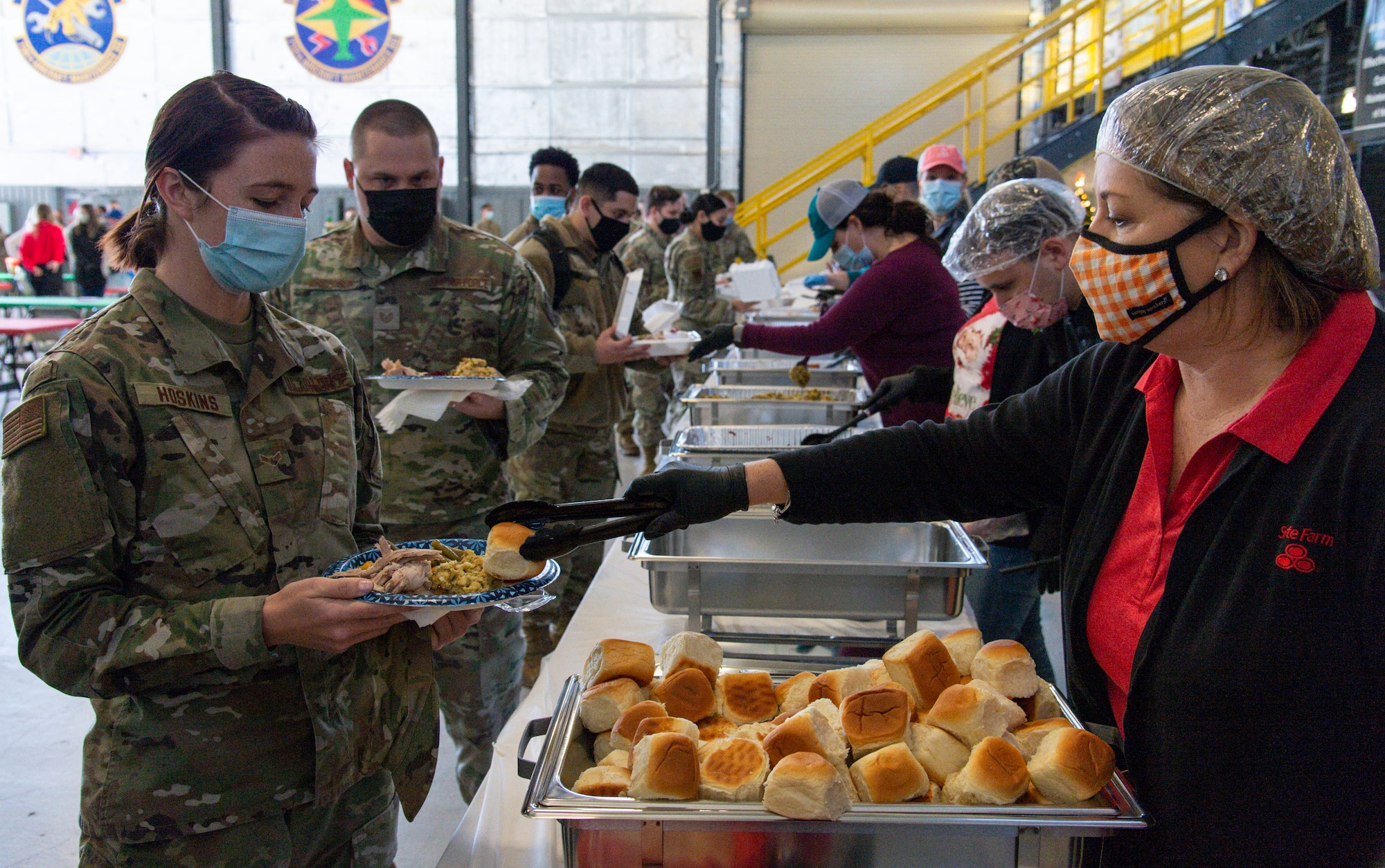 Kelly Brion, Operation Feed the Troops volunteer, serves Airman 1st Class Sarah Hoskins, 436th Communications Squadron cyber operations server management technician, during OFTT on Dover Air Force Base, Delaware, Dec. 14, 2021. More than 30 volunteers served a traditional holiday meal to Team Dover members. (U.S. Air Force photo by Roland Balik)