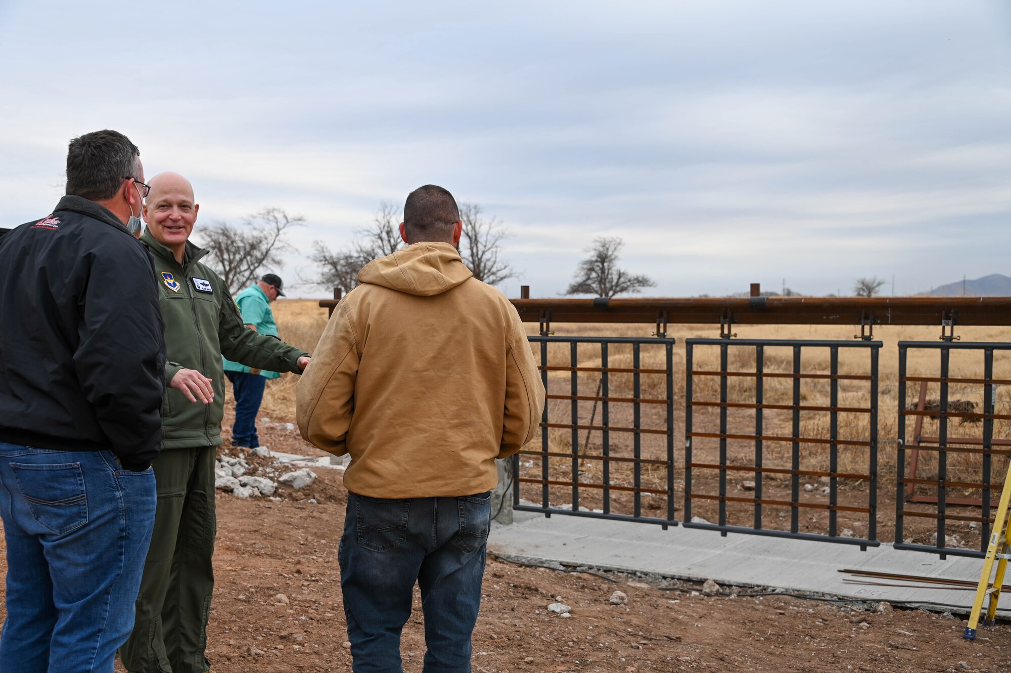 U.S. Air Force Col. Blaine Baker, 97th Air Mobility Wing commander, talks with 97th Civil Engineering Squadron members about the new portion of the fence at Altus Air Force Base, Oklahoma, Dec. 17, 2021. A total of eight gates have been constructed, with one on the south side of the base built by contractors. (U.S. Air Force photo by Airman 1st Class Kayla Christenson)