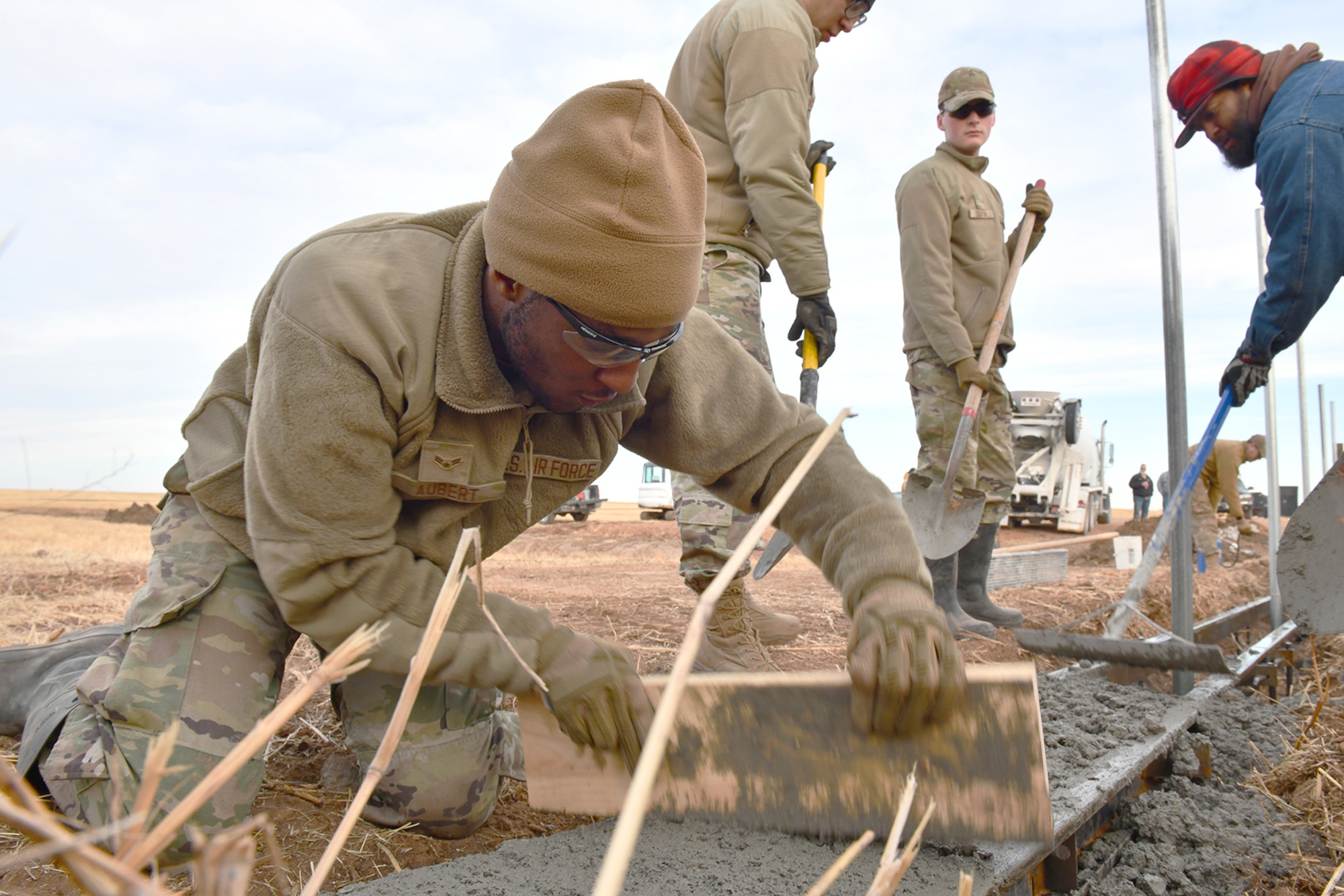 U.S. Air Force Airman 1st Class Miquel Aubert, 97th Civil Engineer Squadron (CES) pavements and construction equipment apprentice, uses a board to float freshly poured concrete at Altus Air Force Base, Oklahoma, Dec. 9, 2021. The concrete is the foundation of a frangible flood gate designed by the 97 CES to prevent damage to the base’s permit fence during rain events. (U.S. Air Force photo by Tech. Sgt. Robert Sizelove)