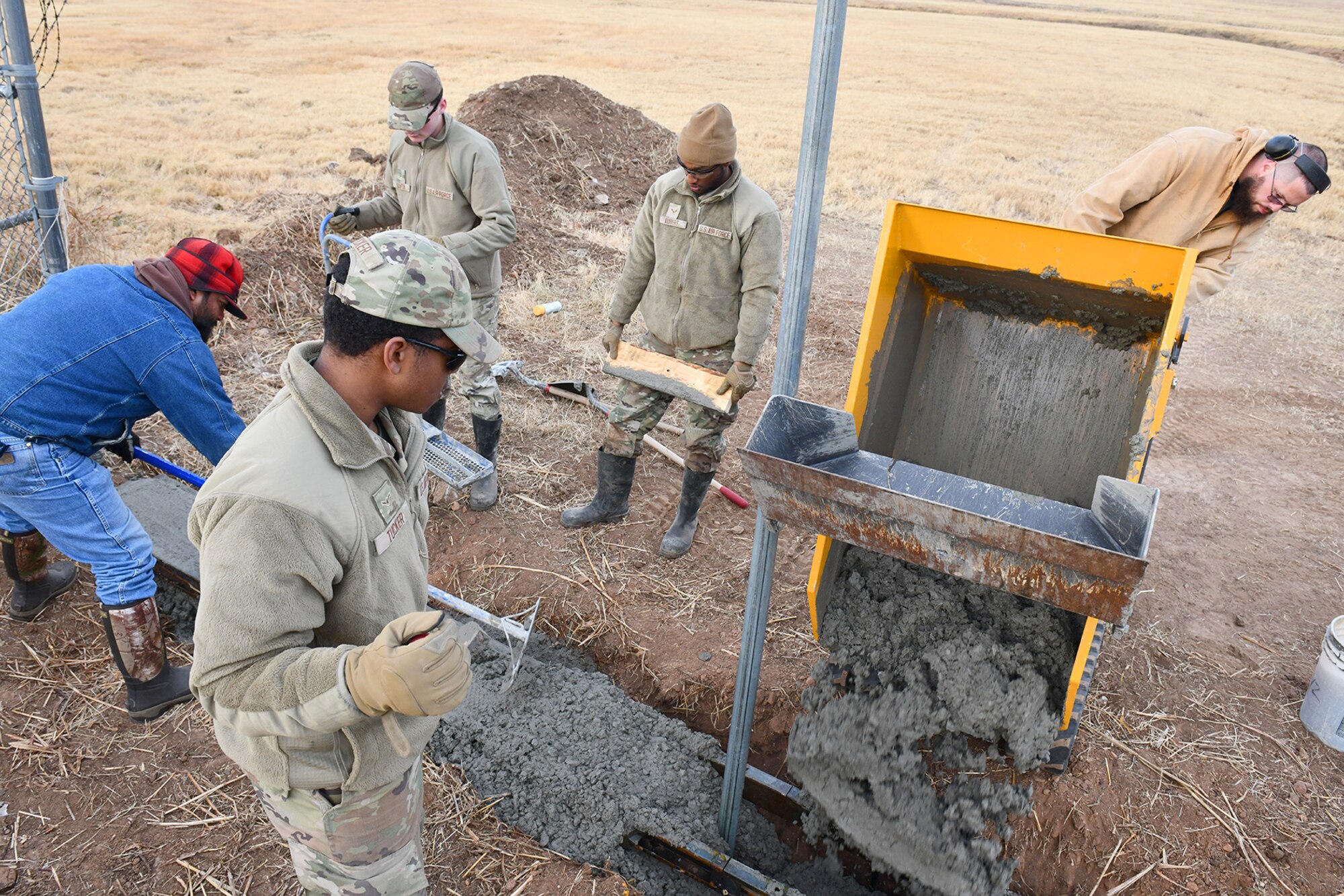 Members of the 97th Civil Engineer Squadron (CES) pour and work concrete during construction of a frangible flood gate at Altus Air Force Base, Oklahoma, Dec. 9, 2021. This is the seventh such gate designed and built by the 97 CES, with an eighth gate on the south side of the base built by contractors. (U.S. Air Force photo by Tech. Sgt. Robert Sizelove)