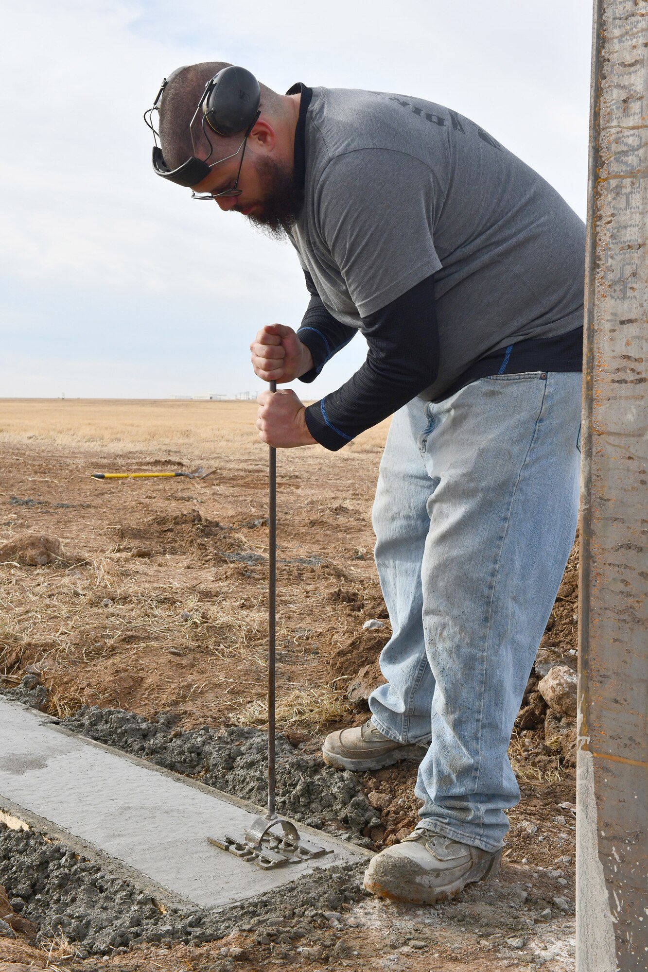 Michael McCoy, 97th Civil Engineer Squadron (CES) equipment operator, stamps a “Dirt Boyz'' emblem into the concrete foundation of a new frangible flood gate at Altus Air Force Base, Oklahoma, Dec. 9, 2021. Designed by the 97 CES to break on purpose, the gates can easily be ‘reset’ after a rain event by replacing an inexpensive and readily available locking mechanism. (U.S. Air Force photo by Tech. Sgt. Robert Sizelove)