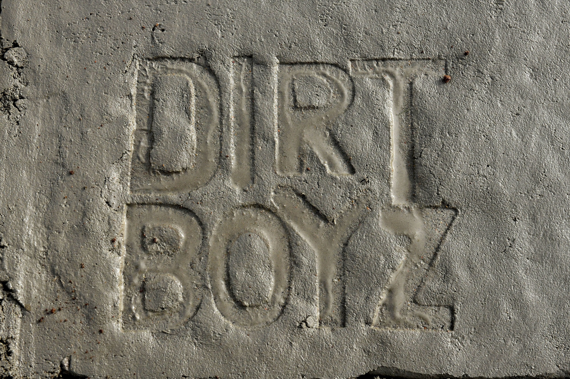 Stamped into fresh concrete, the “Dirt Boyz” emblem marks the foundation of a new frangible flood gate being constructed by 97th Civil Engineer Squadron (CES) at Altus Air Force Base, Oklahoma, Dec. 9, 2021. One of the missions of the 97 CES is to support the training, airlift and refueling missions of the 97th Air Mobility Wing by providing facilities and infrastructure such as these new flood gates. (U.S. Air Force photo by Tech. Sgt. Robert Sizelove)