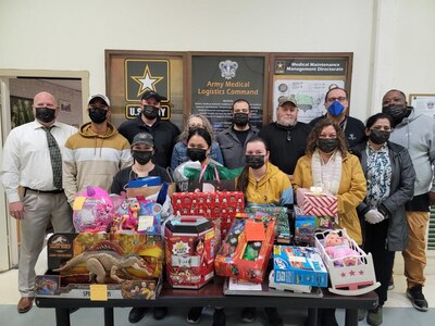 Team members from the U.S. Army Medical Materiel Agency’s Medical Maintenance Operations Division in Tracy, California, are pictured with gifts purchased to support the Adopt-A-Family program on the installation. In their first year participating, the group of 18 employees provided gifts for 11 children from five families. (U.S. Army photo courtesy Isaac Newman)