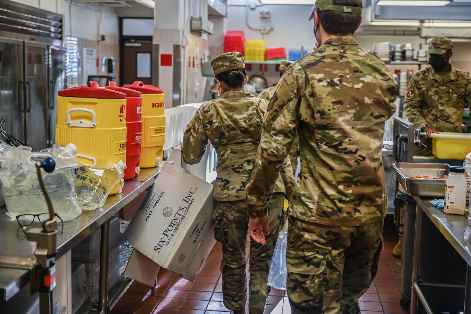 Staff Sgt. Sarah Sanez, 647th Force Support Squadron food service supervisor, and Senior Airman Joseph McCabe, 647th FSS food service journeyman, distribute potable water throughout the Hale Aina Dining Facility at Joint Base Pearl Harbor-Hickam, Hawaii, Dec. 16, 2021. Food service personnel utilize up to 80 gallons of potable water per day to prepare food and clean cookware as a precautionary measure. The water source at the facility is one of 17 locations regularly screened for contaminants on the Hickam side of JBPHH. (U.S. Air Force photo by Staff Sgt. Alan Ricker)