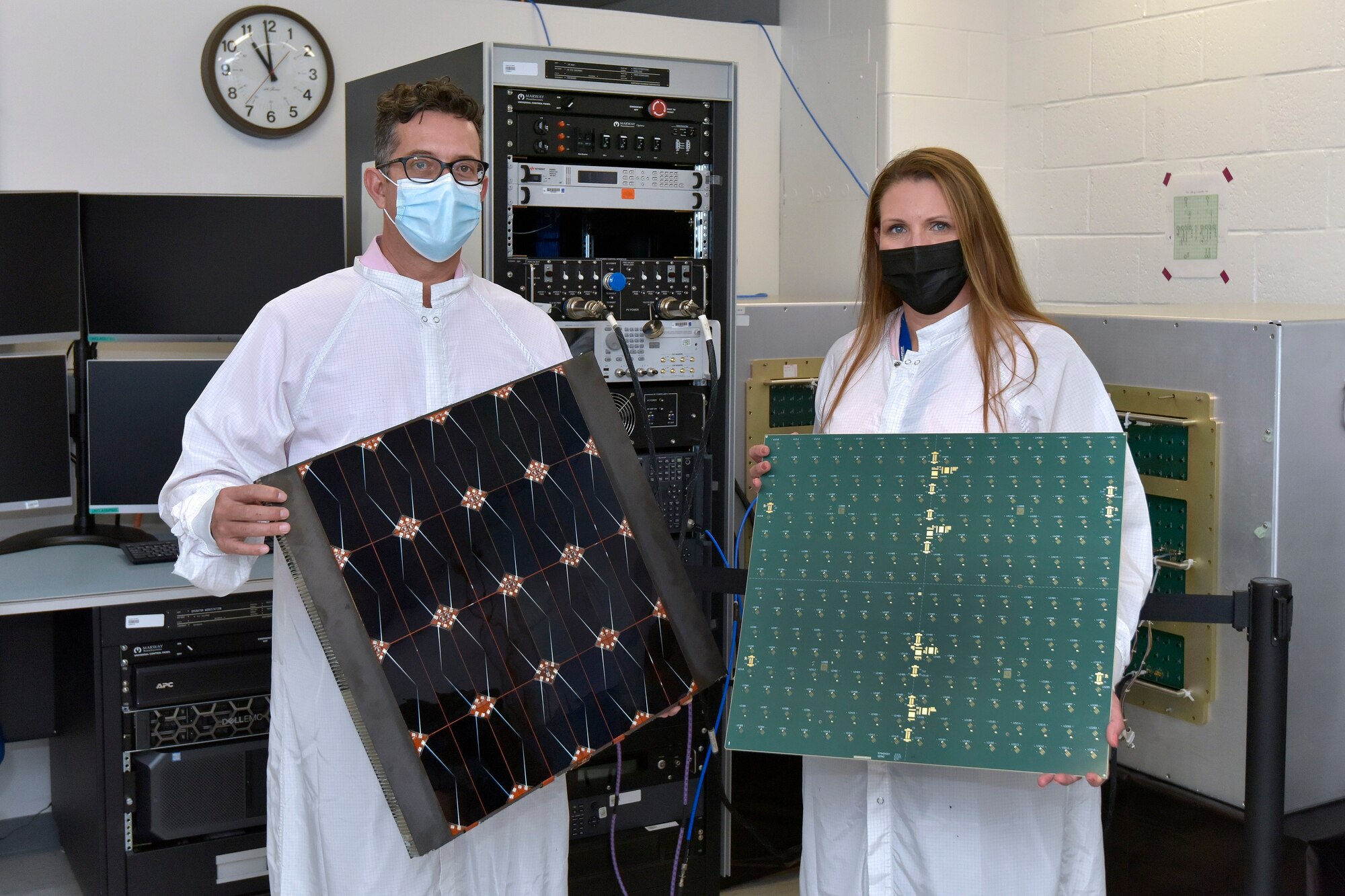 Project Managers James Winter (Air Force Research Laboratory) and Tara Theret (Northrop Grumman) hold models of the photovoltaic and the radio frequency sides of the sandwich tile, while at the Linthicum, Maryland facility, to witness the conversion and beaming experiment. (Courtesy photo/Northrop Grumman)
