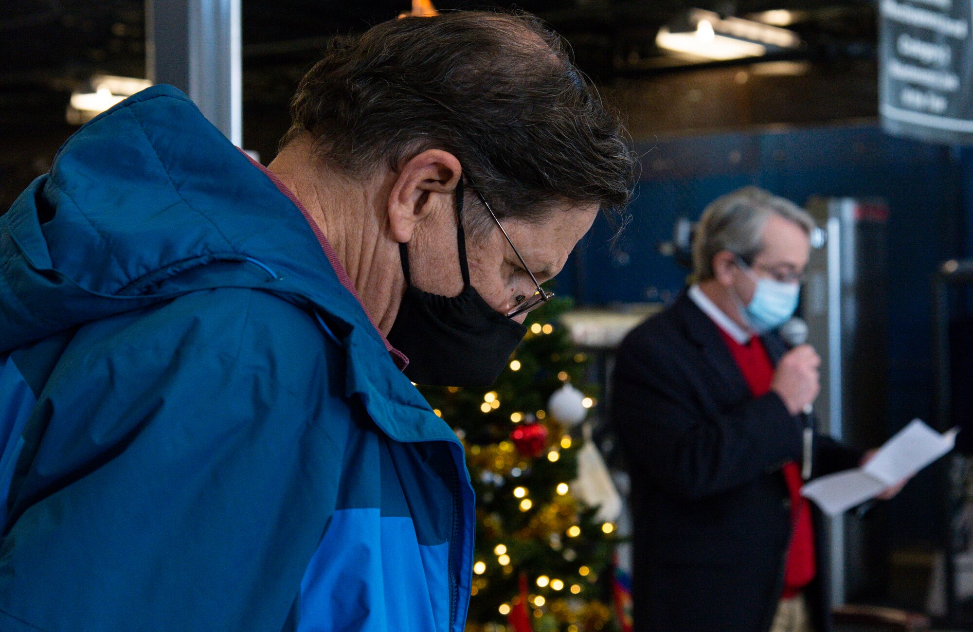 Retired Master Sgt. Robert Reese, Operation Feed the Troops organizer , bows his head as Father Charles Weiss, Church of Christ in Dover, Delaware, delivers the blessing prior to the OFTT on Dover Air Force Base, Delaware, Dec. 14, 2021. Reese and more than 30 volunteers helped serve a traditional holiday meal to more than 900 Team Dover members. Fifty-two turkeys were donated and prepared by local businesses for the event. (U.S. Air Force photo by Roland Balik)