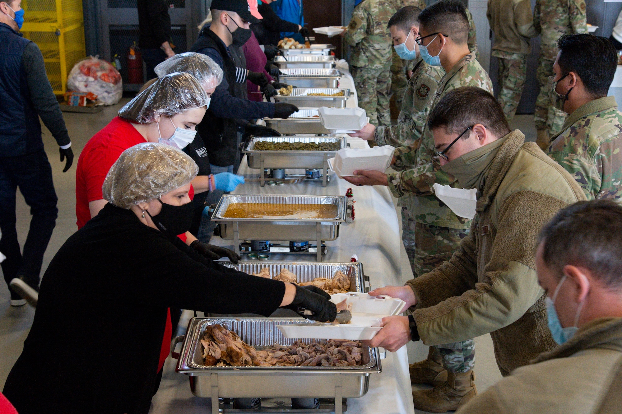 Volunteers serve Team Dover members as they move through the serving line during Operation Feed the Troops on Dover Air Force Base, Delaware, Dec. 14, 2021. OFTT volunteers served a traditional holiday meal to more than 900 Team Dover members. (U.S. Air Force photo by Roland Balik)