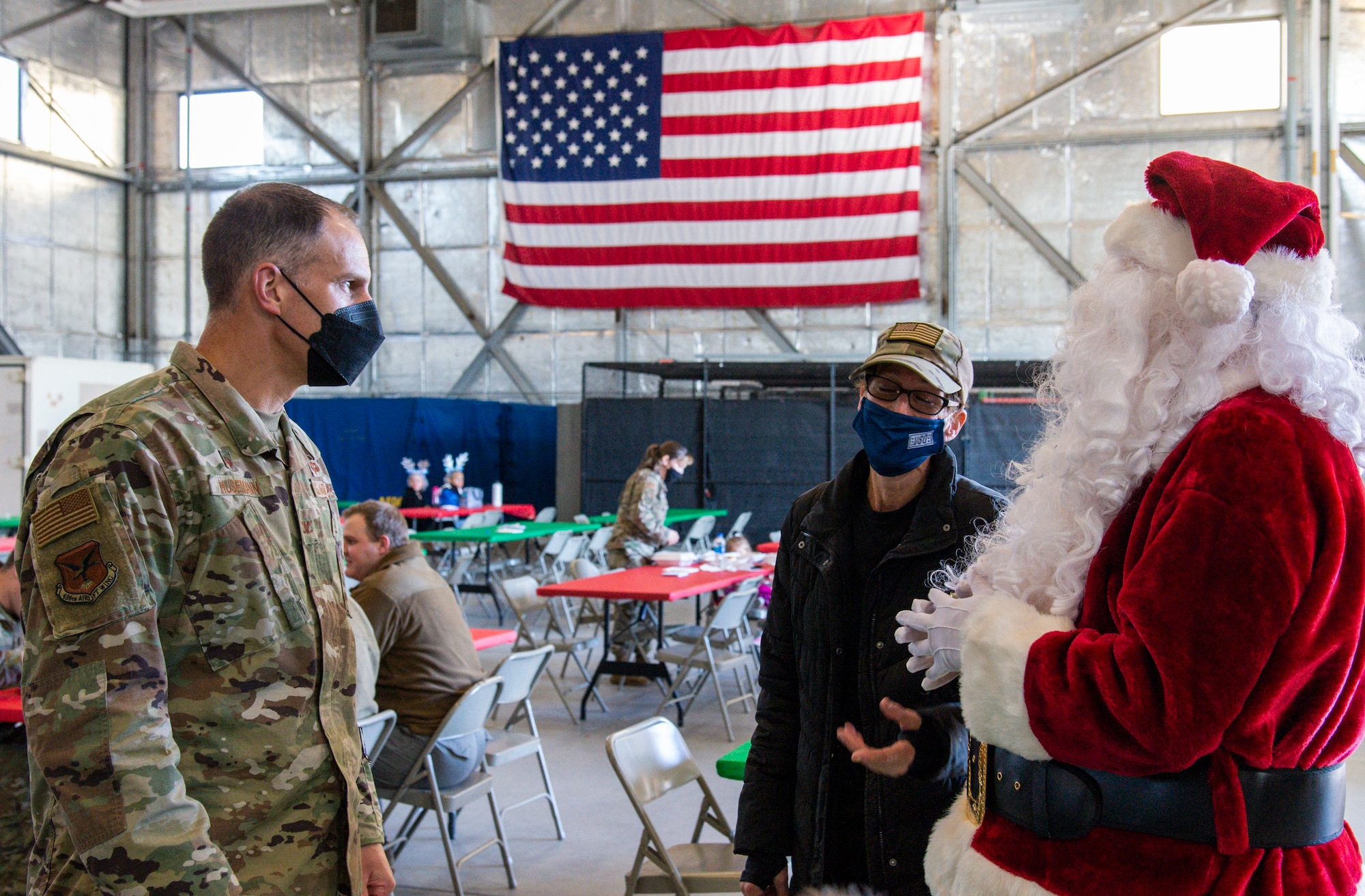 From left, Col. Matt Husemann, 436th Airlift Wing commander, and Jennifer Rambo, 436th AW honorary commander, speak with Santa Claus during Operation Feed the Troops on Dover Air Force Base, Delaware, Dec. 14, 2021. OFTT volunteers served a traditional holiday meal to more than 900 Team Dover members.  Fifty-two turkeys were donated and prepared by local businesses for the event. (U.S. Air Force photo by Roland Balik)