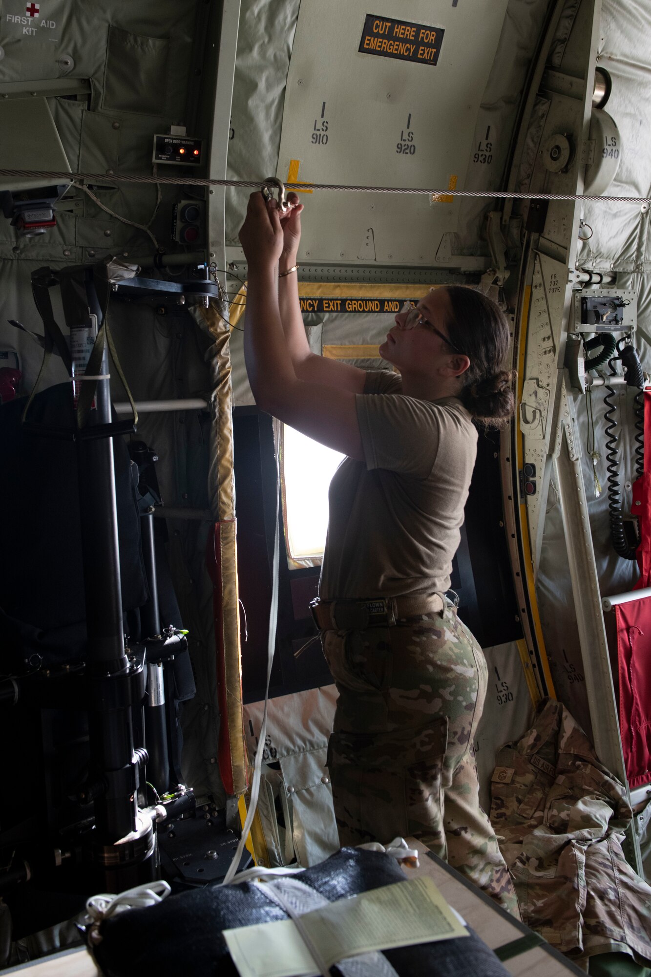 Senior Airman Kim Doyle, 36th Airlift Squadron loadmaster, attaches a cord to deploy a parachute to a line during the 70th Anniversary of Operation Christmas Drop drops at Andersen Air Force Base, Guam, Dec. 6, 2021. OCD is the Department of Defense’s longest-running humanitarian aid and disaster relief training mission and provides relief to more than 55 islands throughout the Pacific. Operations such as OCD provide the U.S. and its partners the opportunity to enhance joint operational capabilities and maintain preparedness for real-world emergencies. (U.S. Air Force photo by Tech. Sgt. Joshua Edwards)