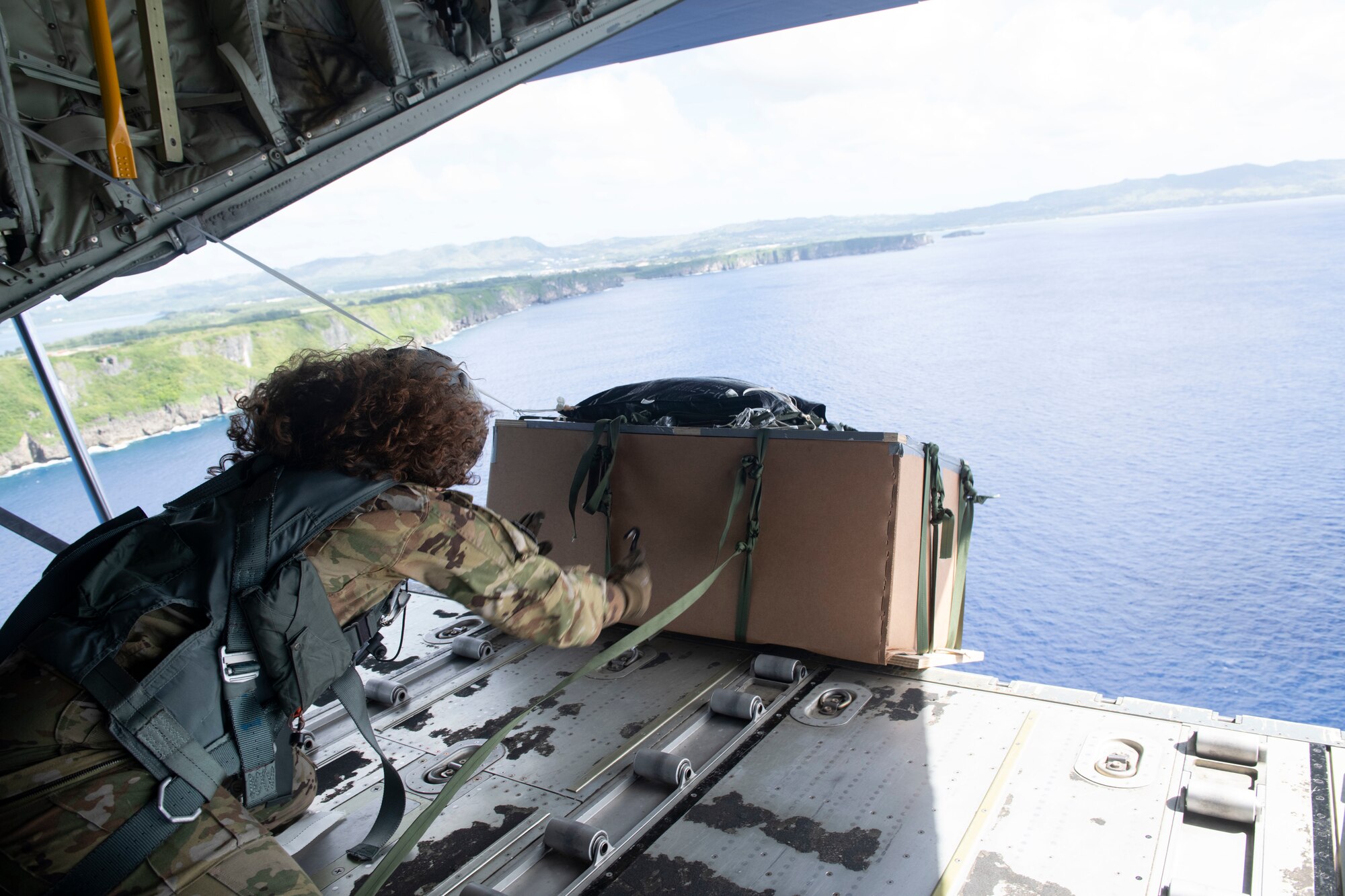 Senior Airman Kim Doyle, 36th Airlift Squadron loadmaster, releases a bundle near Orote Dec. 3, 2021, for the 70th Anniversary of Operation Christmas Drop. OCD is the Department of Defense’s longest-running humanitarian assistance and disaster relief training mission and provides relief to more than 55 islands throughout the Pacific. Operations such as OCD provide the U.S. and its partners and allies the opportunity to enhance joint operational capabilities and maintain preparedness for real-world emergencies. (U.S. Air Force photo by Tech. Sgt. Joshua Edwards)