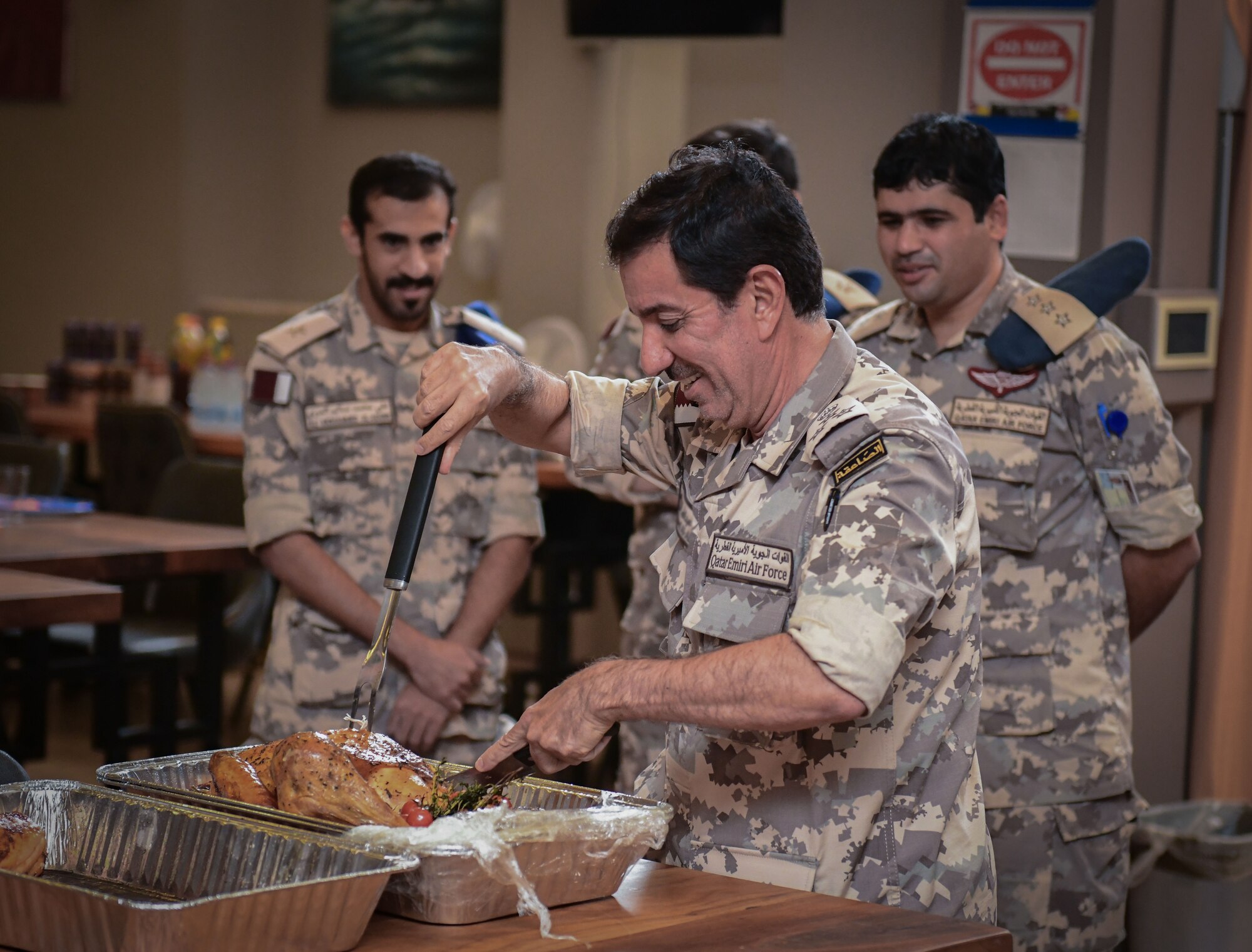 Qatari service member carves turkey during meal.