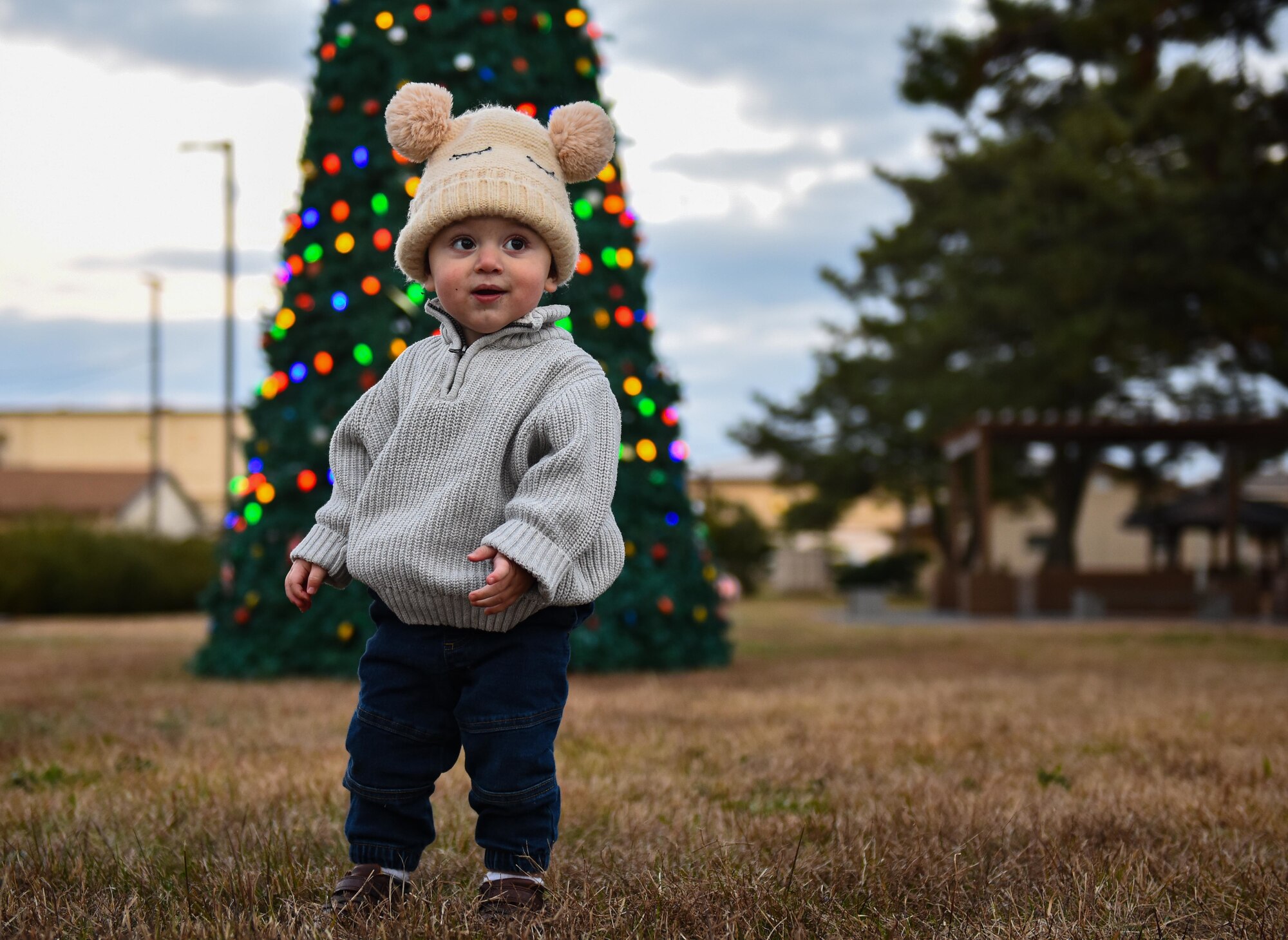 Families and Airmen pose in front of a Christmas tree.