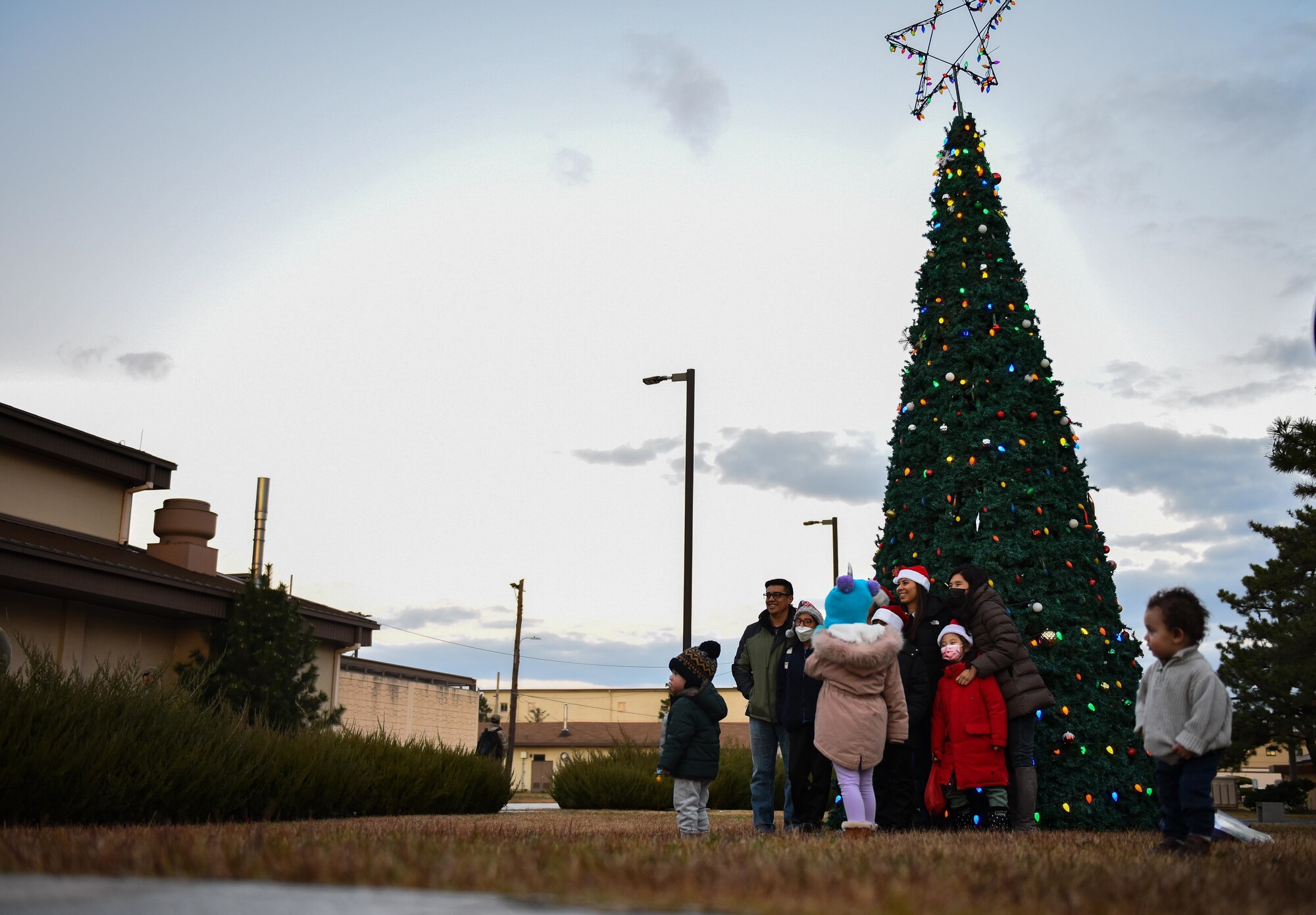 Families and Airmen pose in front of a Christmas tree.