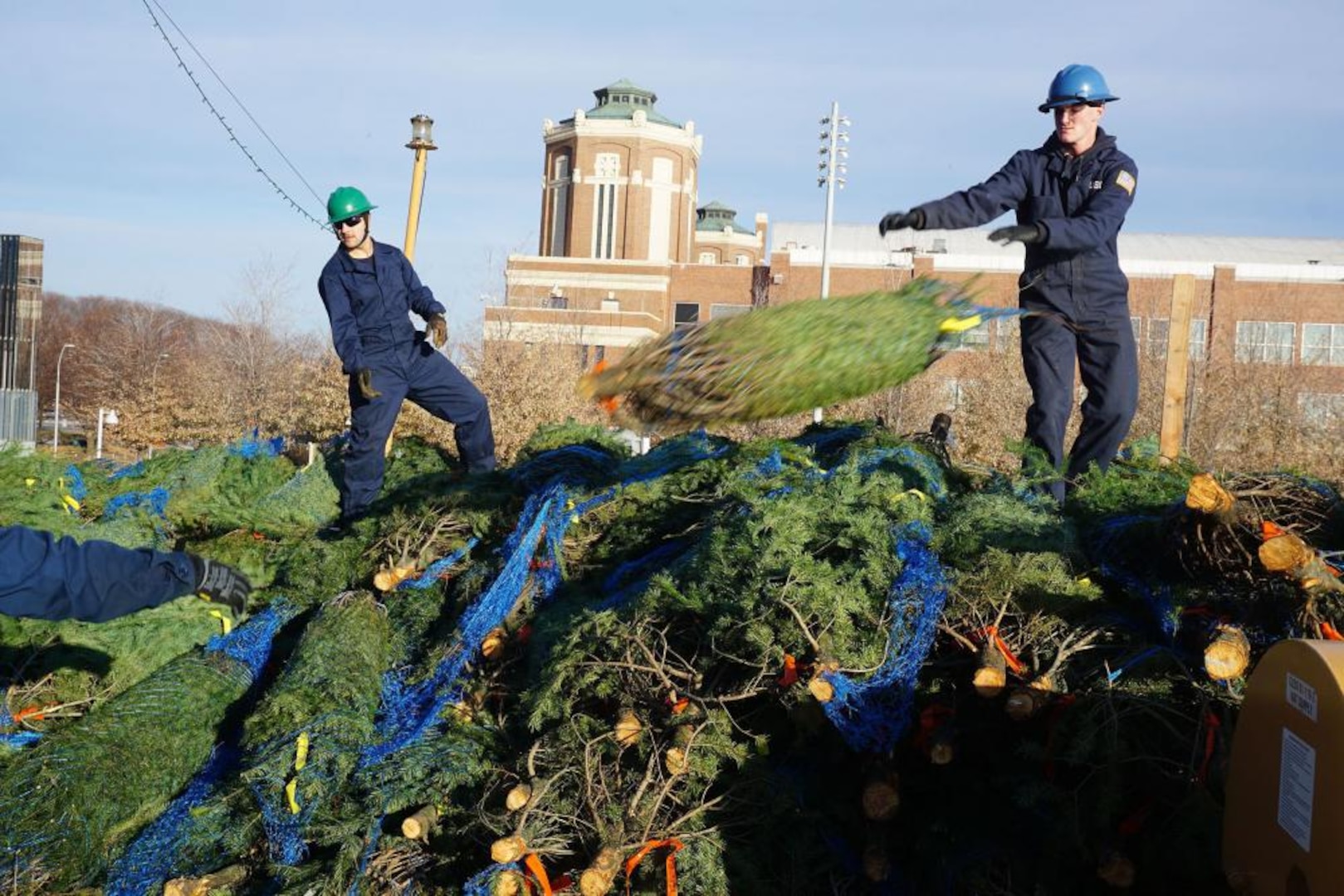 Crew members aboard Coast Guard Cutter Mackinaw unload donated Christmas trees from a pile on the ship's fantail at Chicago's Navy Pier Saturday, Dec. 4, 2021. The trees are among 1,200 bound for Chicago families that otherwise wouldn't have one, thanks to the 22nd annual Chicago's Christmas Ship celebration. U.S. Coast Guard photo by Brian Hinton, U.S. Coast Guard Auxiliary.