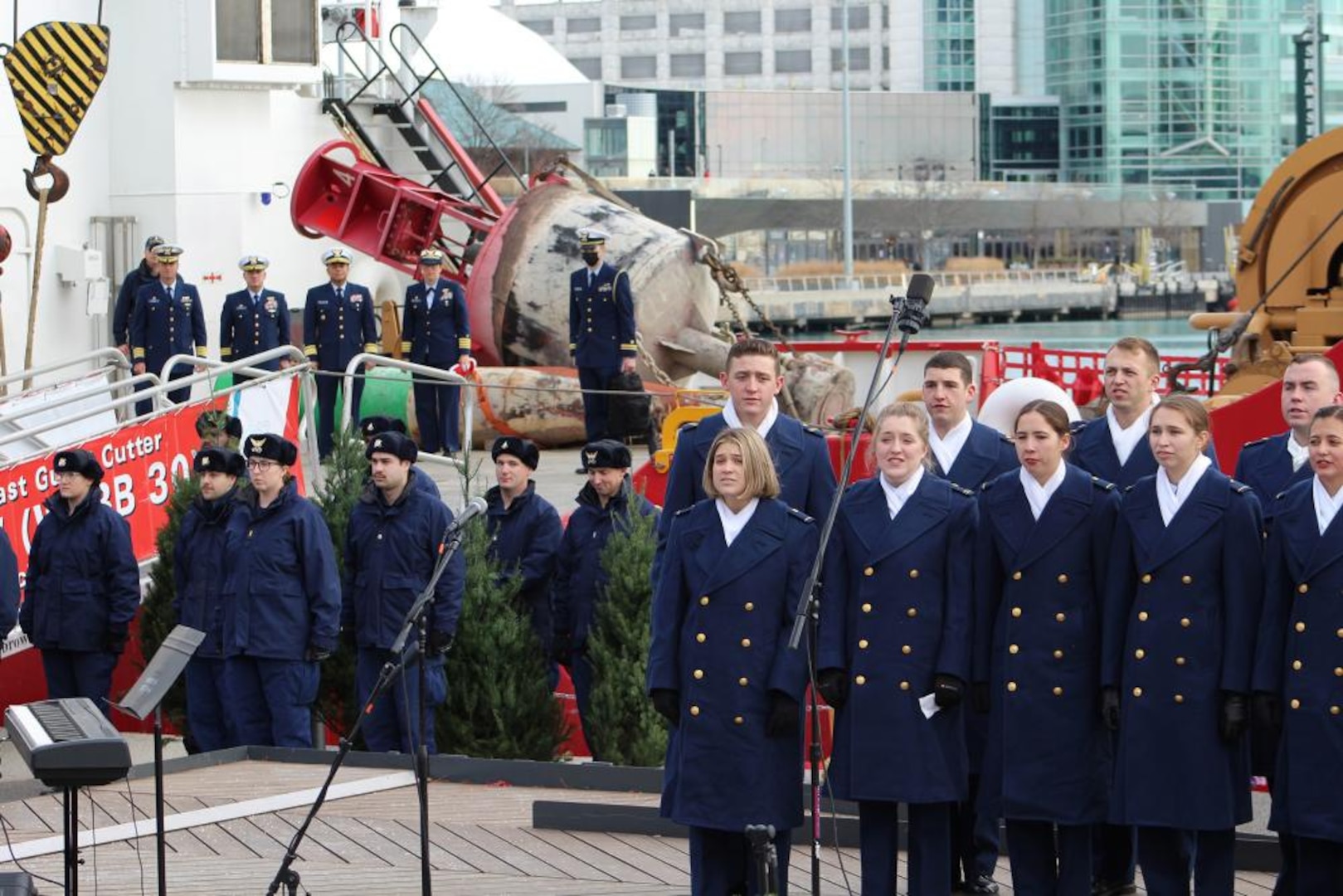The Coast Guard Academy Glee Club performs acapella holiday music for hundreds of spectators as part of Chicago's Christmas Ship ceremonies Dec. 4, 2021, as senior officers and Mackinaw crew members look on. The performance was part of the 22nd annual Christmas Ship celebration, which delivered 1,200 Christmas trees to Chicago families that otherwise would not have had one. U.S. Coast Guard photo by Matthew Thompson, U.S. Coast Guard Auxiliary.