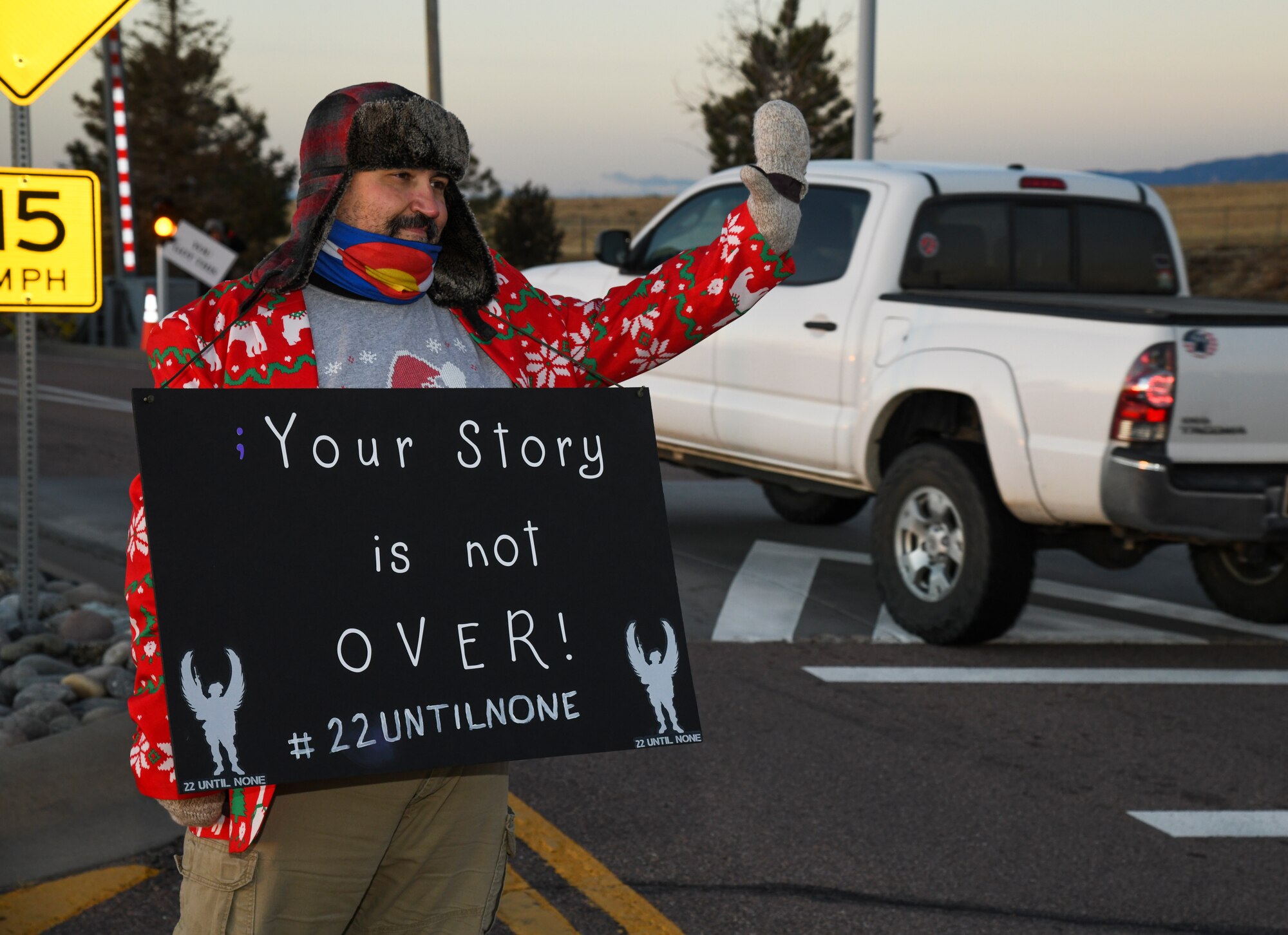 Christopher Ruble, 21st Medical Group x-ray technician, holds a sign at the entrance of the Enoch Gate.
