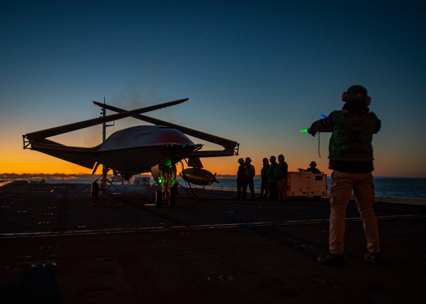 A Boeing unmanned MQ-25 aircraft is given operating directions on the flight deck aboard the aircraft carrier USS George H.W. Bush (CVN 77).