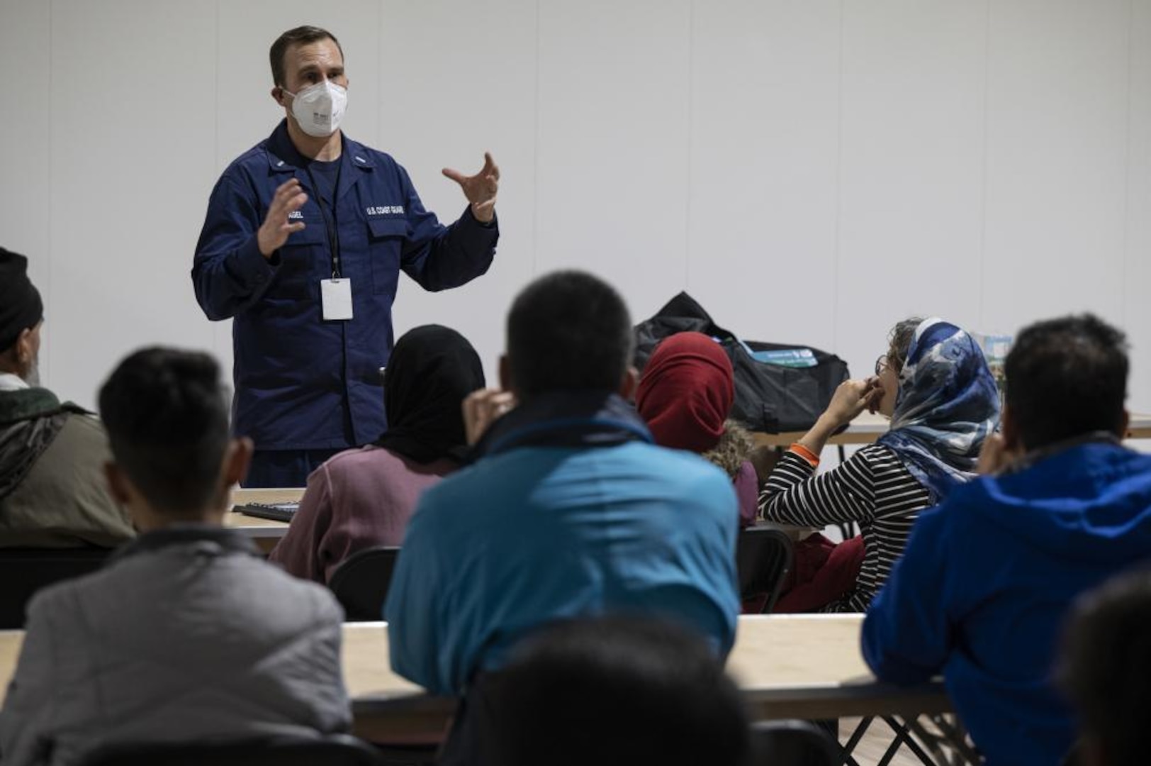 U.S. Coast Guard Lt. j.g. Todd Pagel, Task Force Liberty education director, briefs Afghan guests during teacher orientation in Liberty Village, Joint Base McGuire-Dix-Lakehurst, New Jersey, Dec. 16, 2021. The Department of Defense, through U.S. Northern Command, and in support of the Department of Homeland Security, is providing transportation, temporary housing, medical screening, and general support for at least 11,000 Afghan evacuees at Liberty Village, in permanent or temporary structures, as quickly as possible. This initiative provides Afghan personnel essential support at secure locations outside Afghanistan. (U.S. Air Force photo by Tech. Sgt. Matthew B. Fredericks)