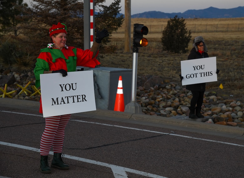 U.S. Air Force Lt. Col. Jessica Ditson, Peterson-Schriever Garrison violence prevention integrator and Angelique McDonald, chief of P-S GAR public affairs mission partner support, hold signs at the Enoch Gate on Schriever Space Force Base, Colorado, Dec. 17, 2021.